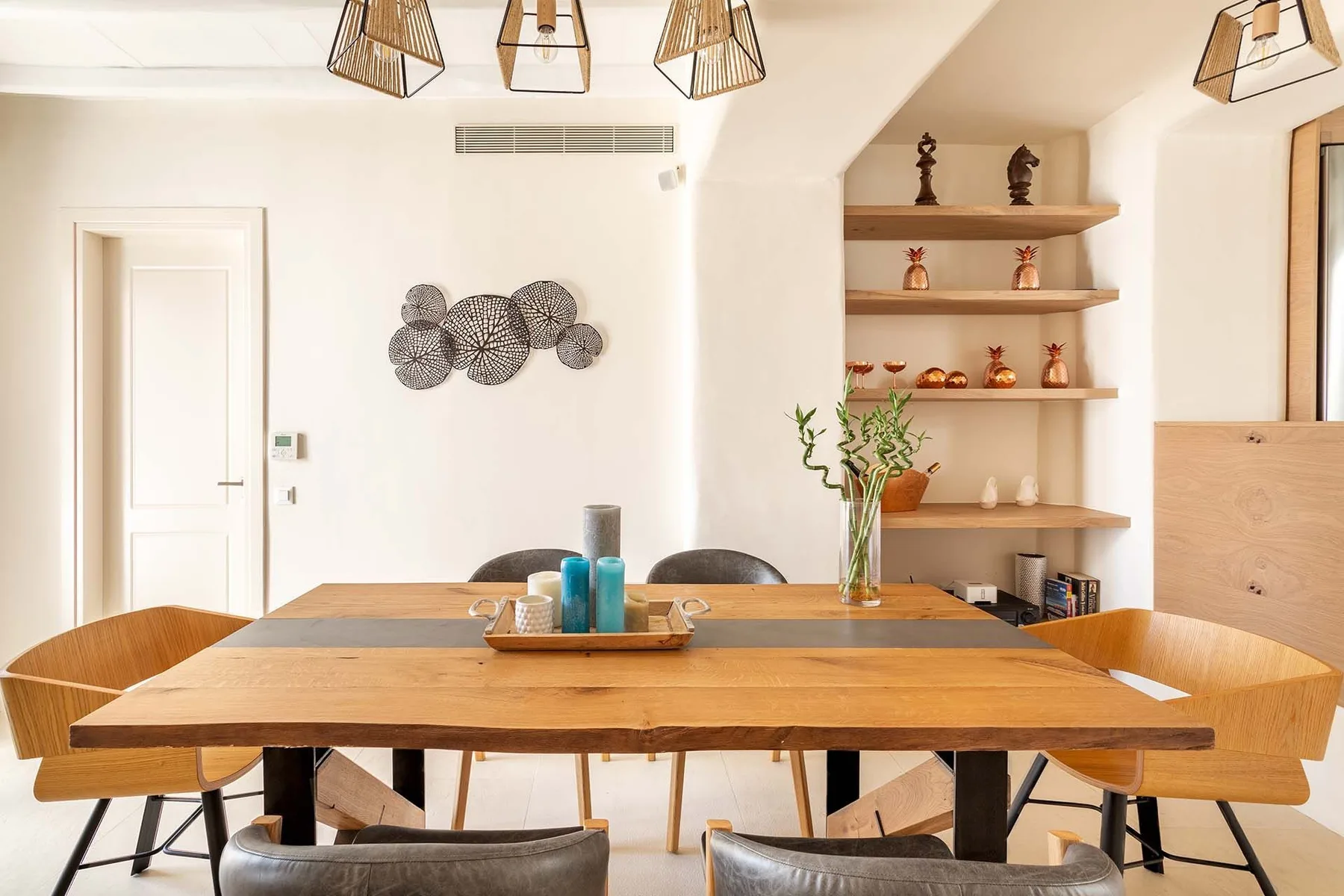 A dining area with a wooden table and open display shelves.