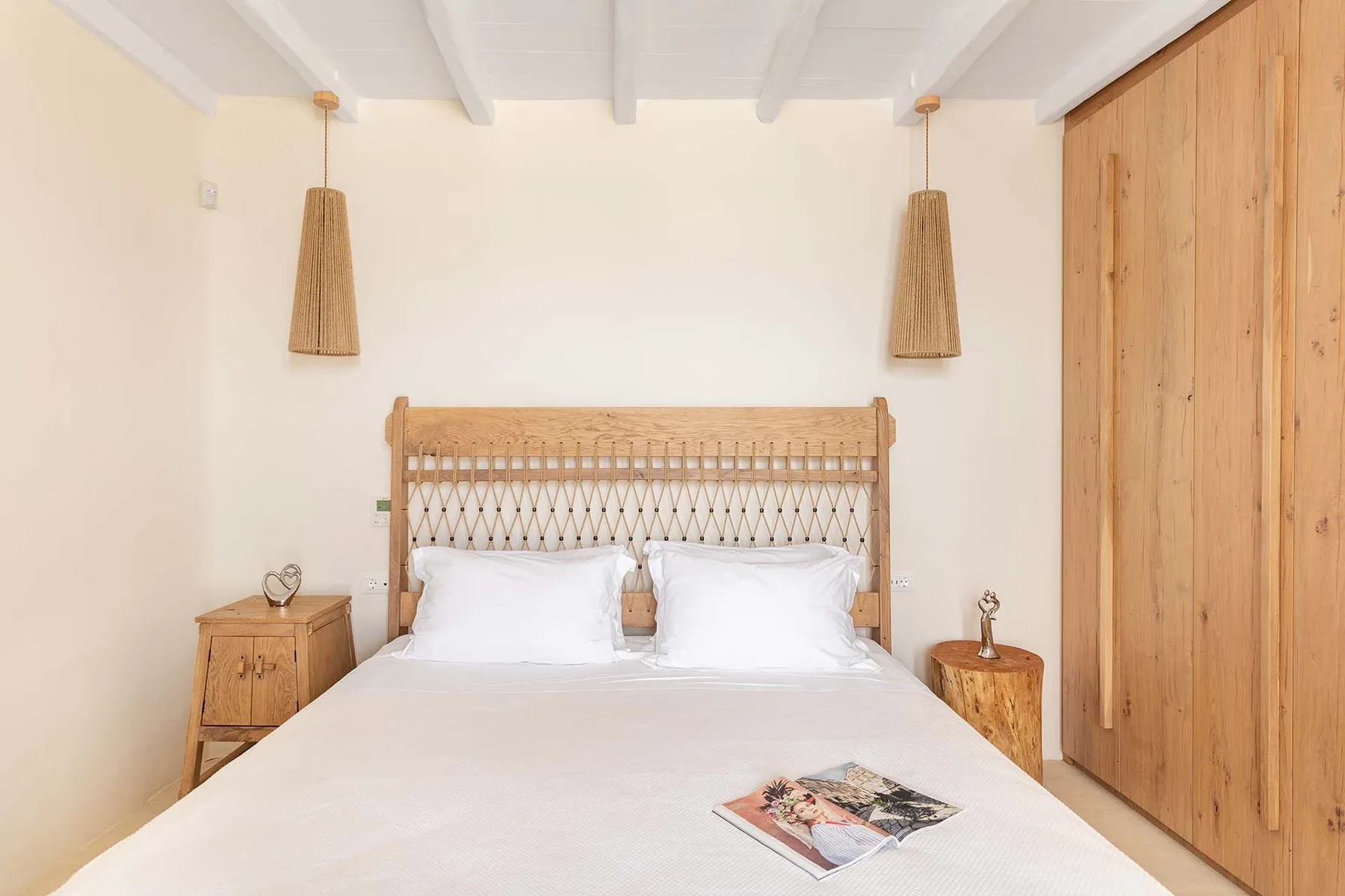 A bedroom with a bed, woven headboard, and wooden wall panels.