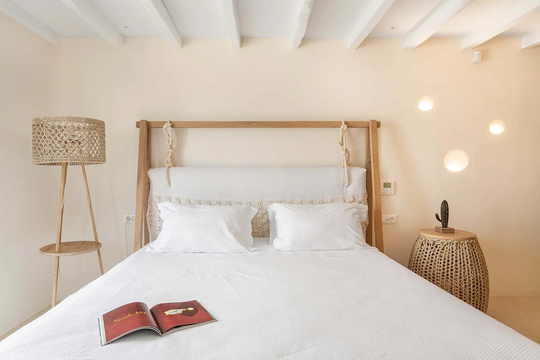 A bright bedroom with a white bed and an open book.