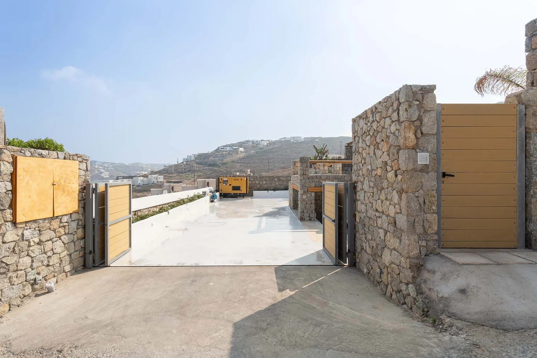 A paved outdoor entrance with stone walls and open gates.