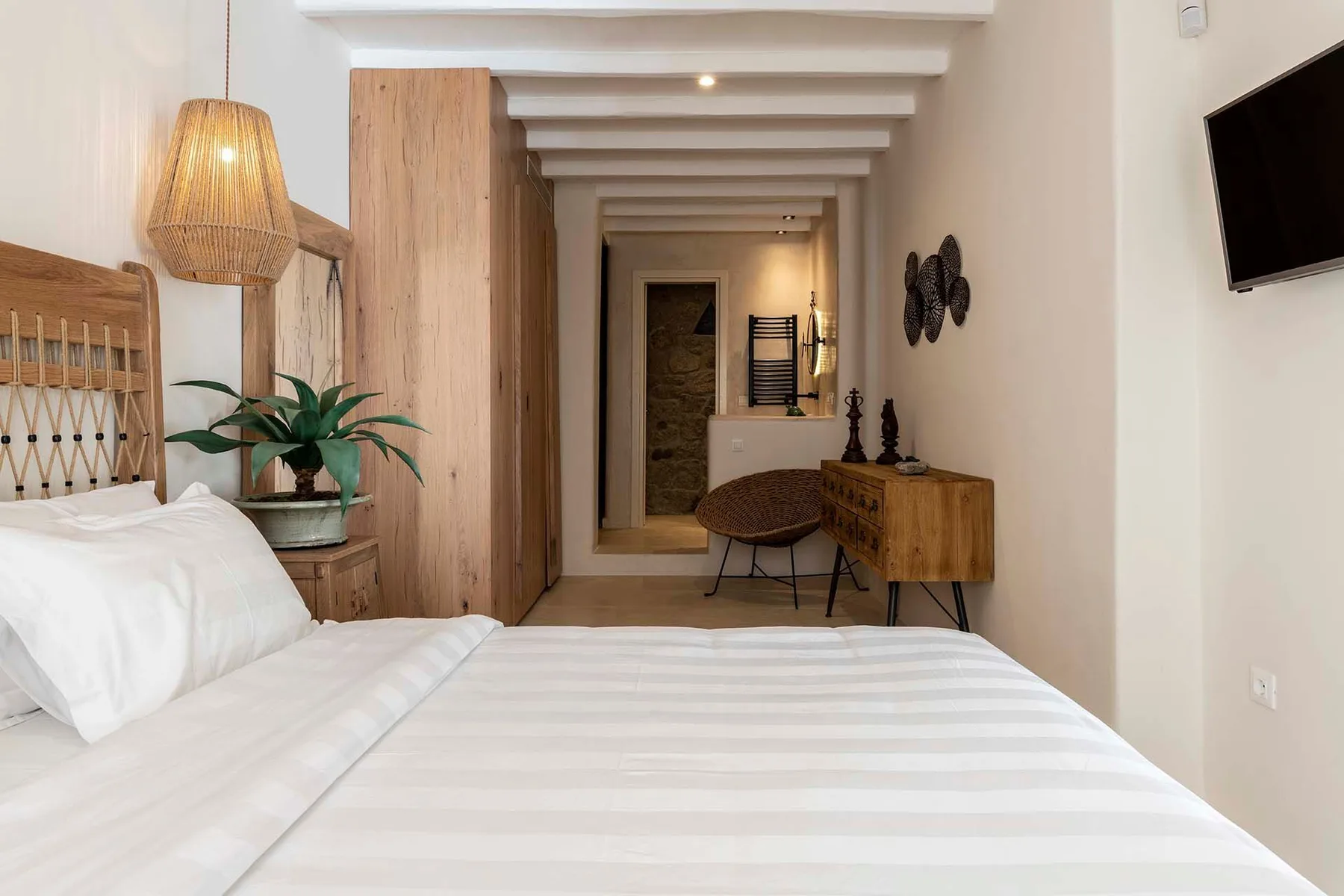 A bedroom with a neatly made bed and a wooden dresser.