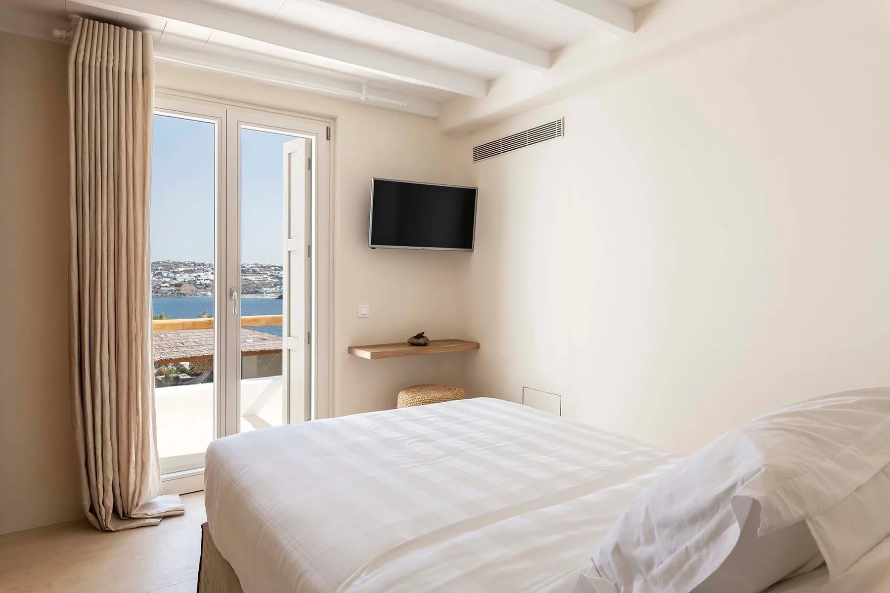 A bedroom with a bed and a glass door opening onto a sea view.