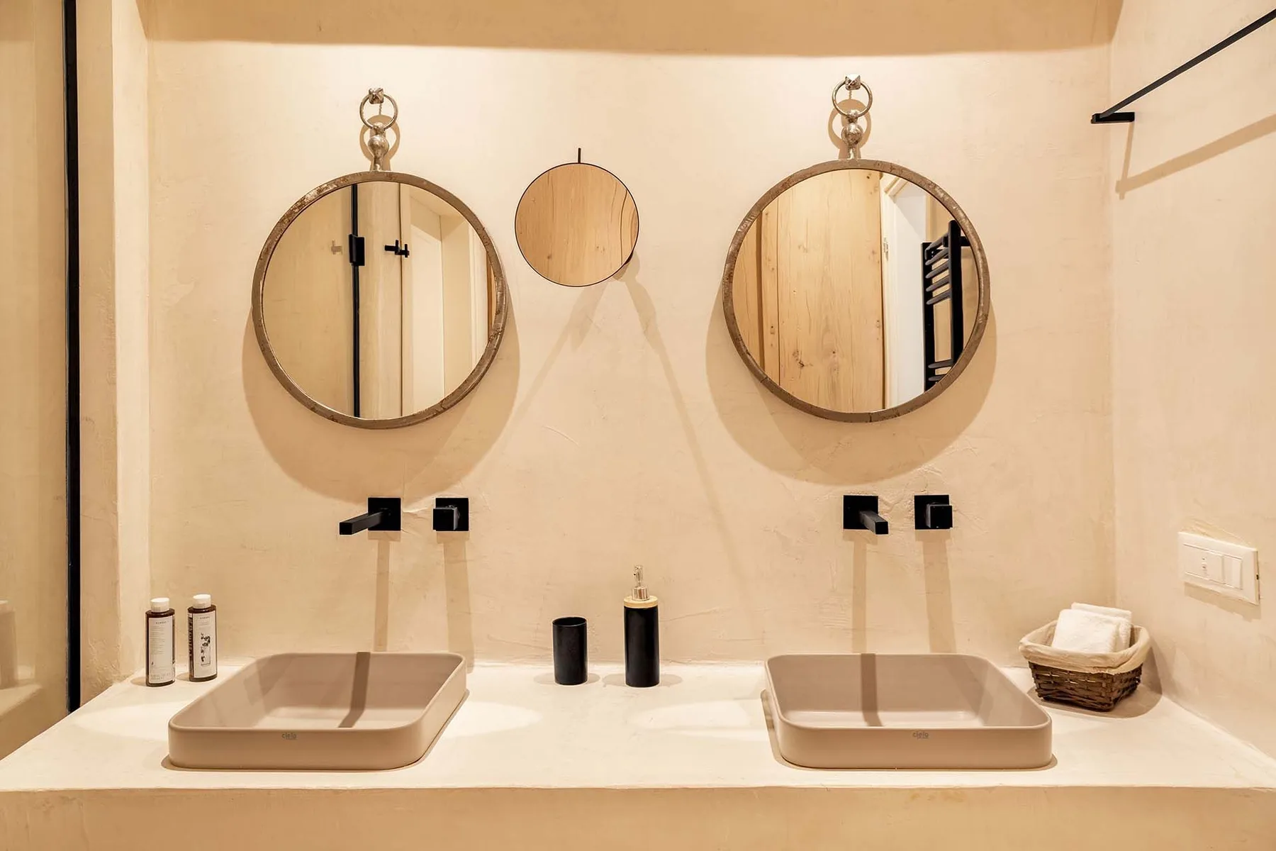 A bathroom vanity with two basins and round mirrors.
