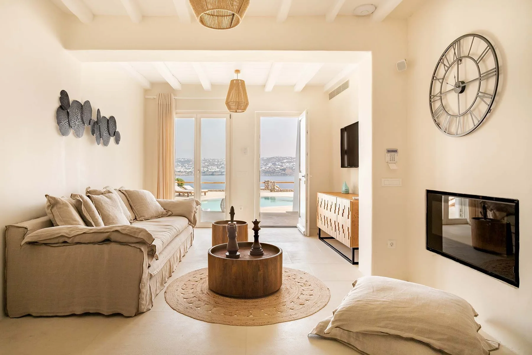 A bright living room with a sofa, round coffee table, and glass doors overlooking the water.