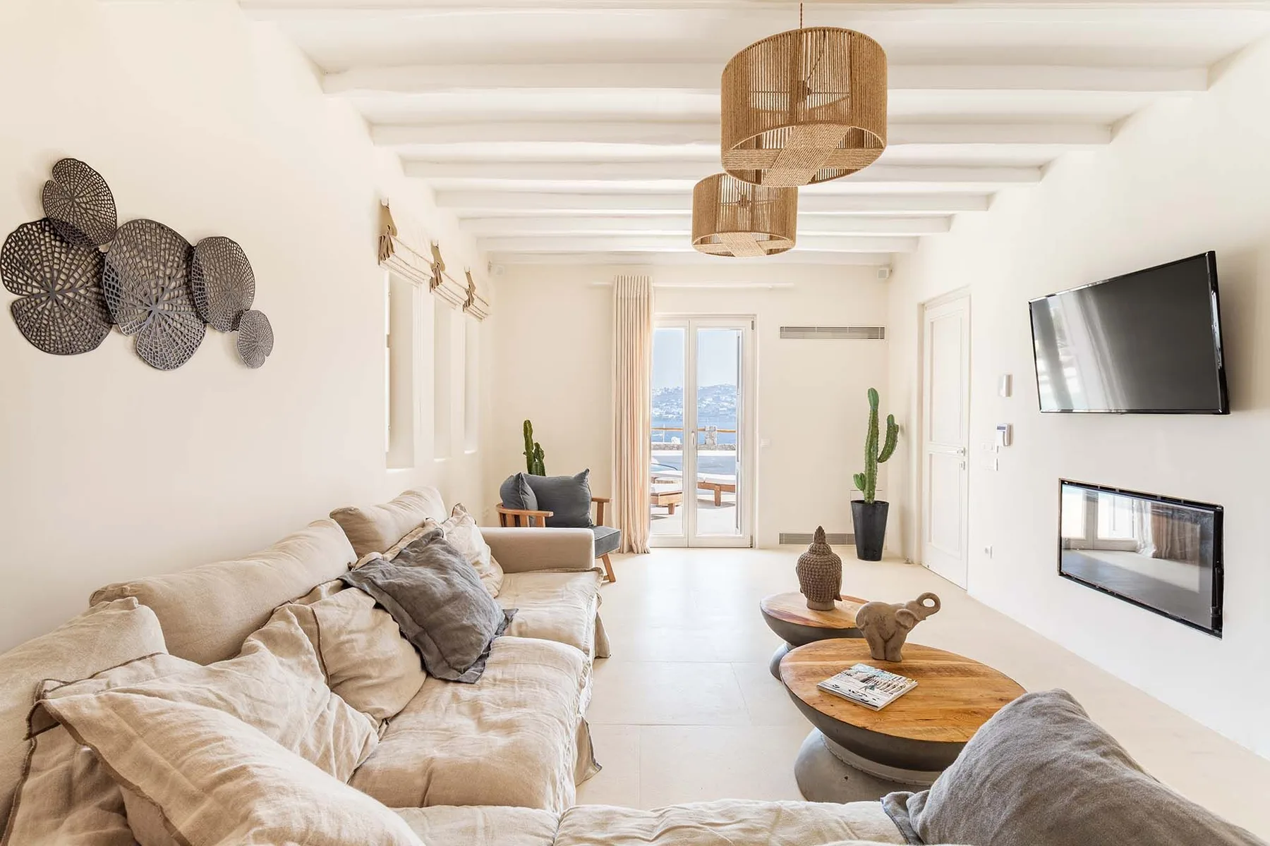 A bright living room with seating, a wall-mounted television, and a coffee table.