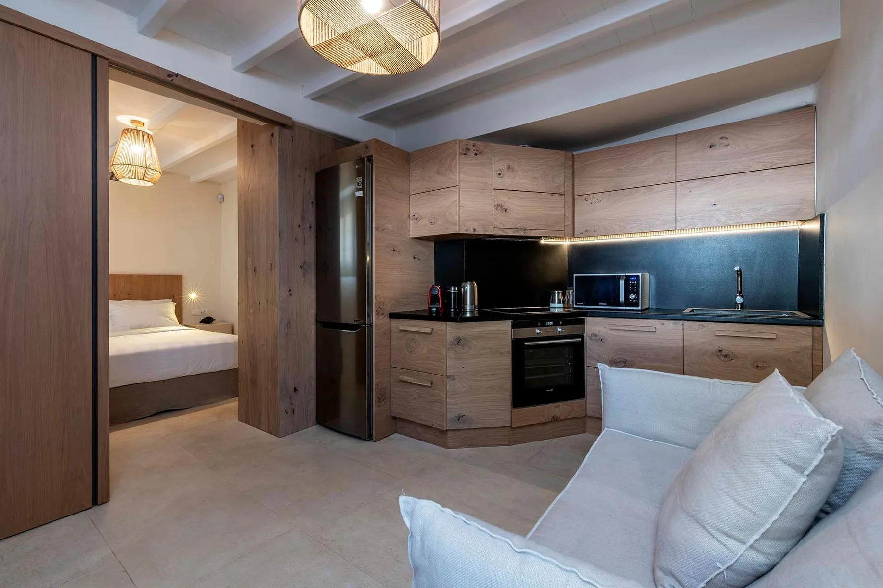 A compact kitchen and seating area with a bedroom visible through the doorway.