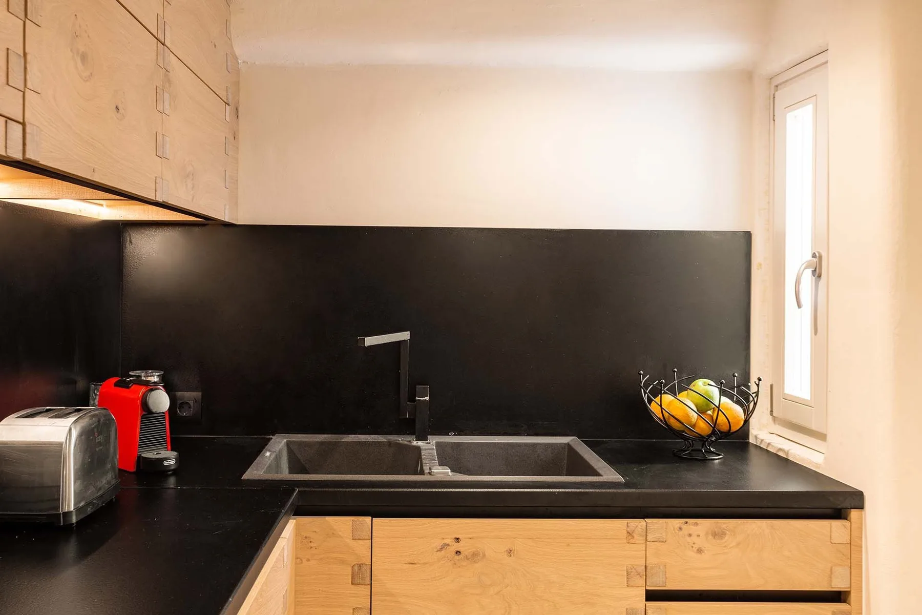 A kitchen counter with a sink, coffee maker, and bowl of fruit.