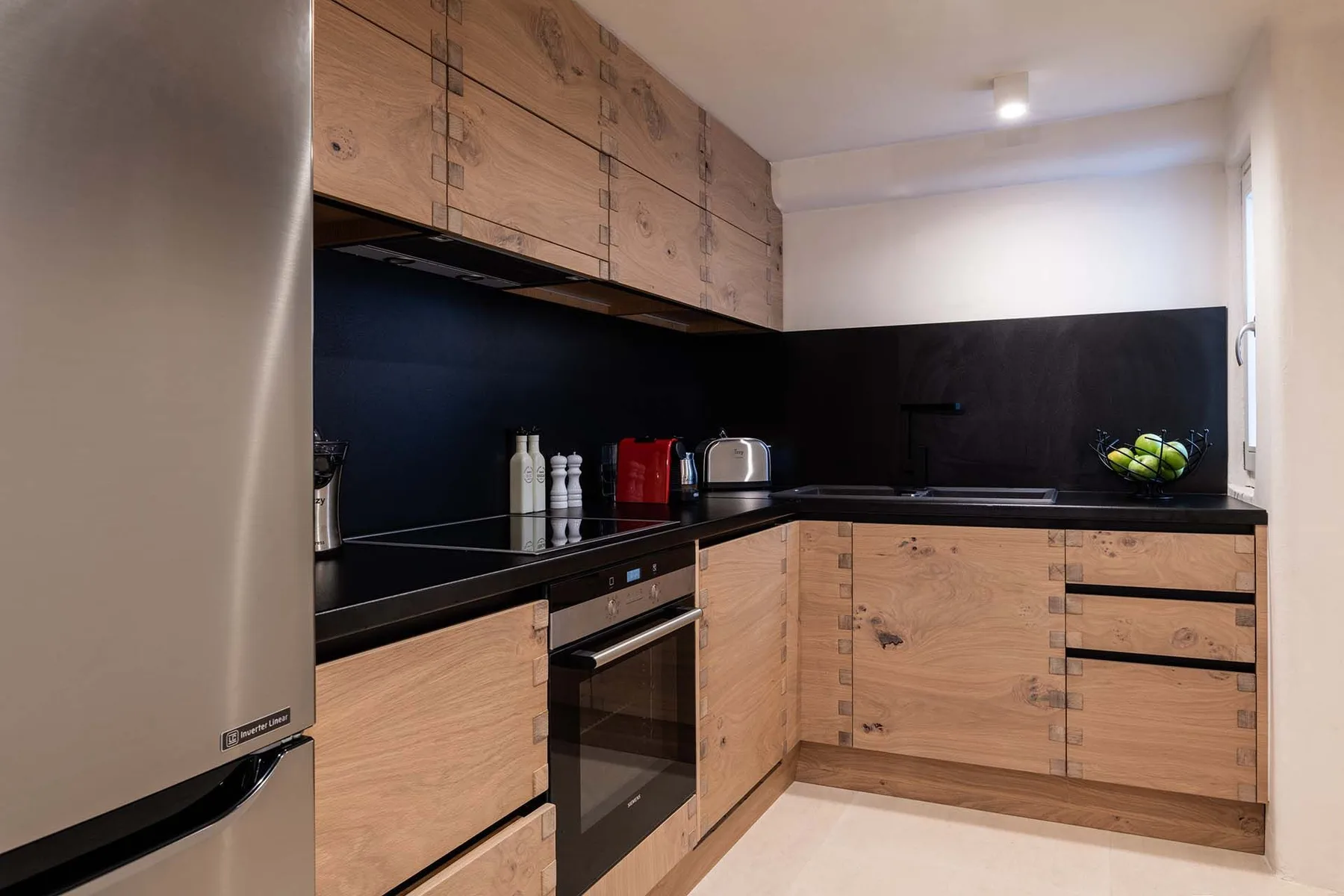 A modern kitchen with light wood cabinets and a black countertop.