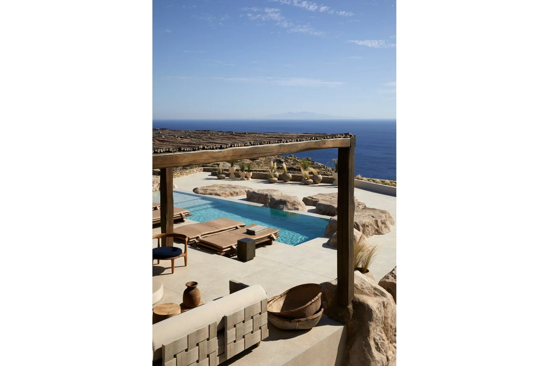 A seaside pool terrace with lounge seating and a clear view of the sea.