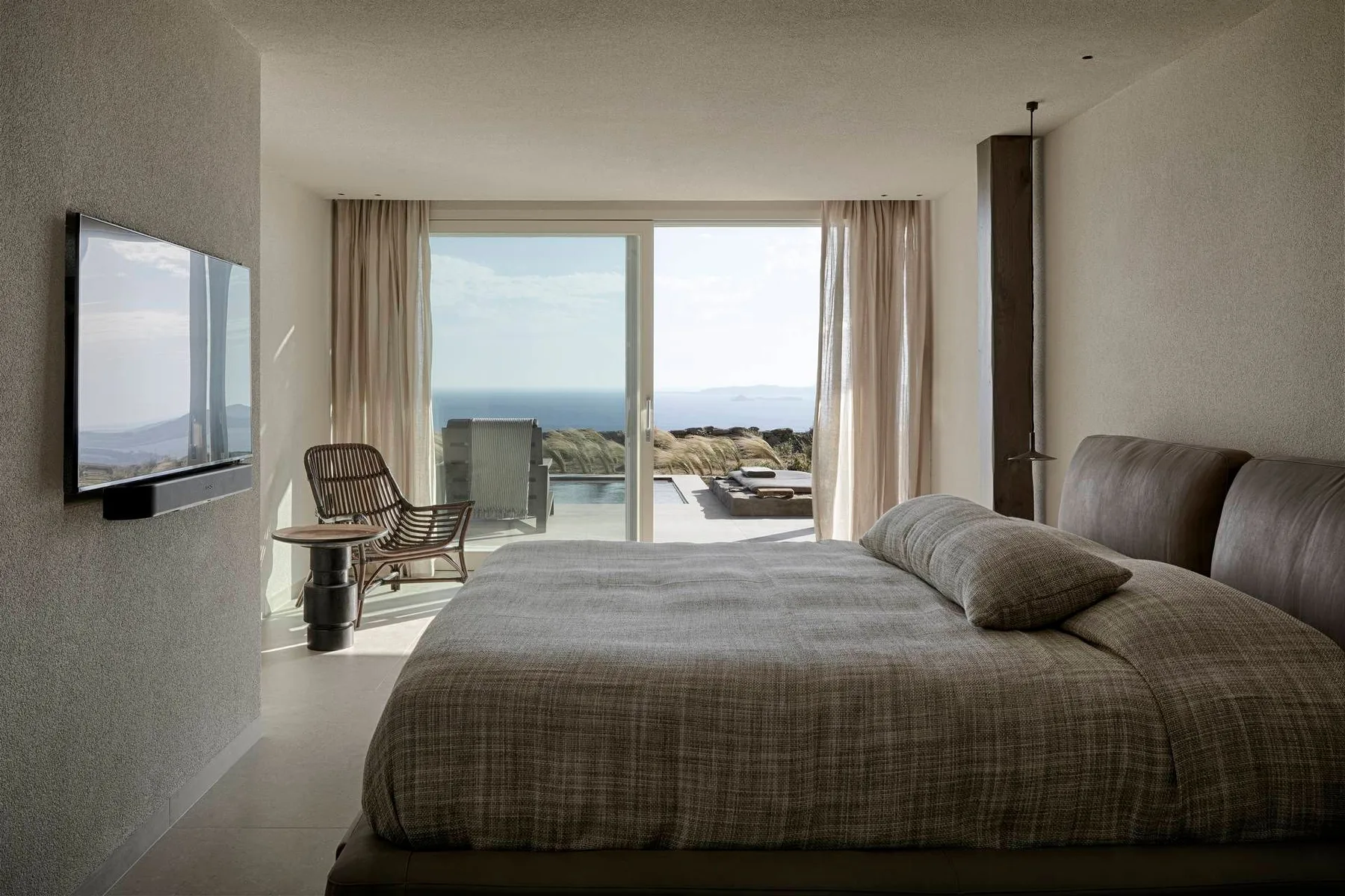 A bedroom with a large bed facing sliding glass doors and a sea view.