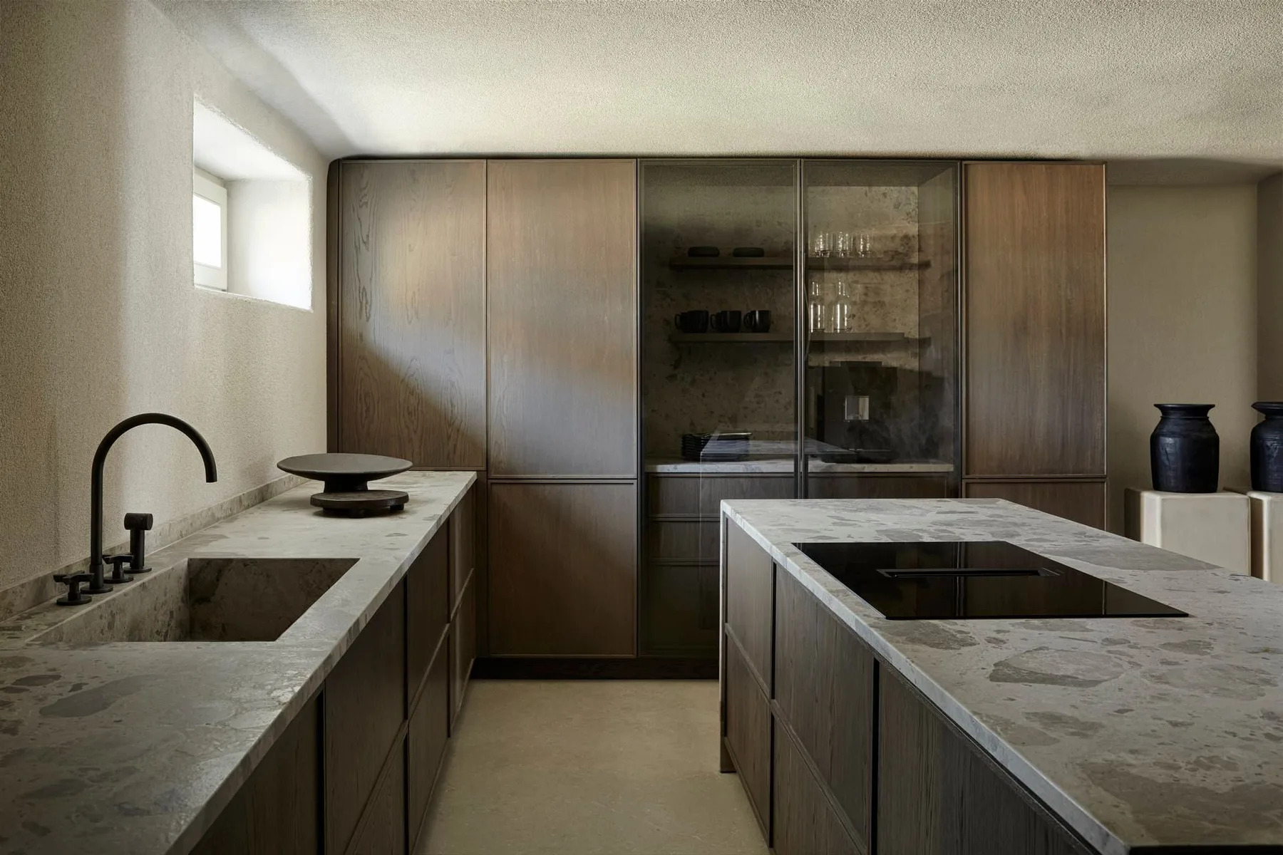 A modern kitchen with stone countertops, cabinetry, and a central island.