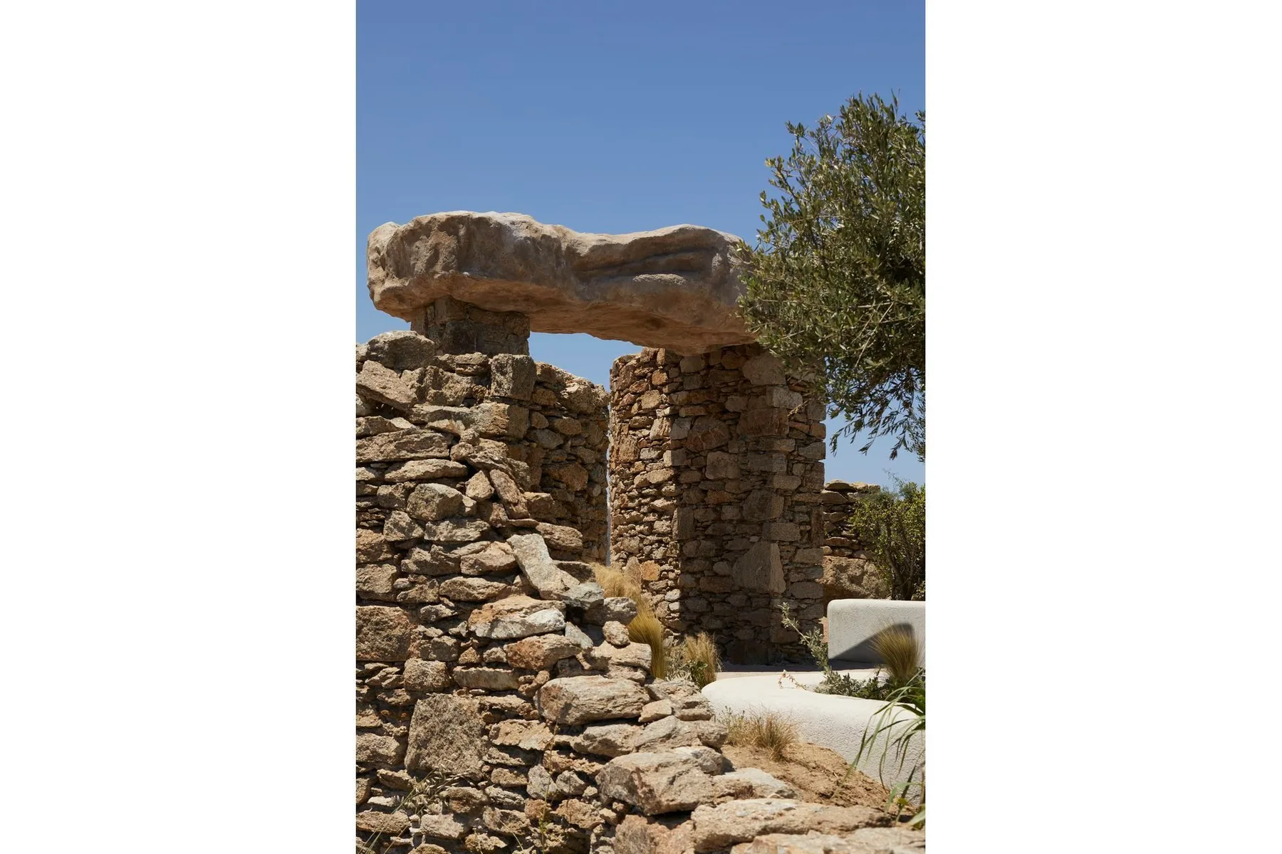 A rustic stone structure with a large stone lintel beneath a clear sky.