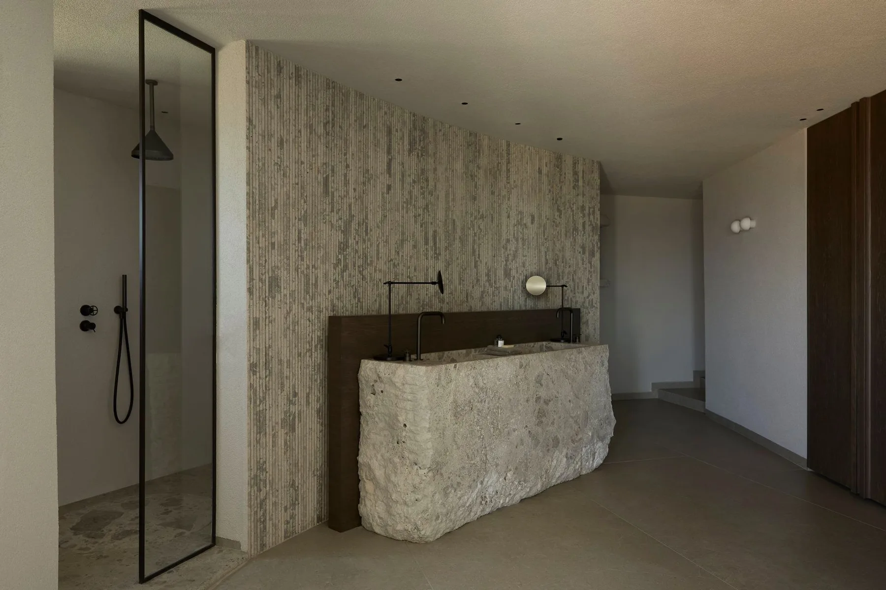 A modern bathroom with a walk-in shower and a stone-fronted vanity.