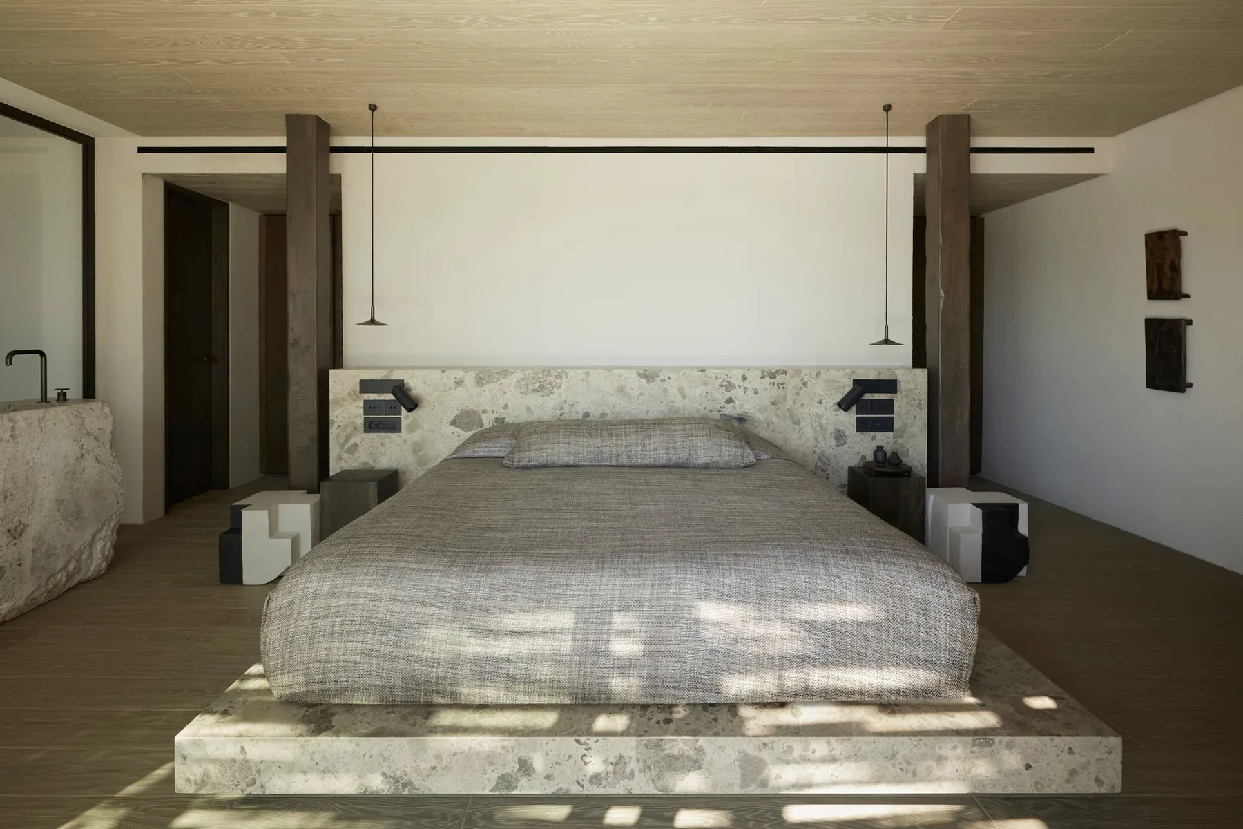 A bedroom with a large bed and stone headboard.