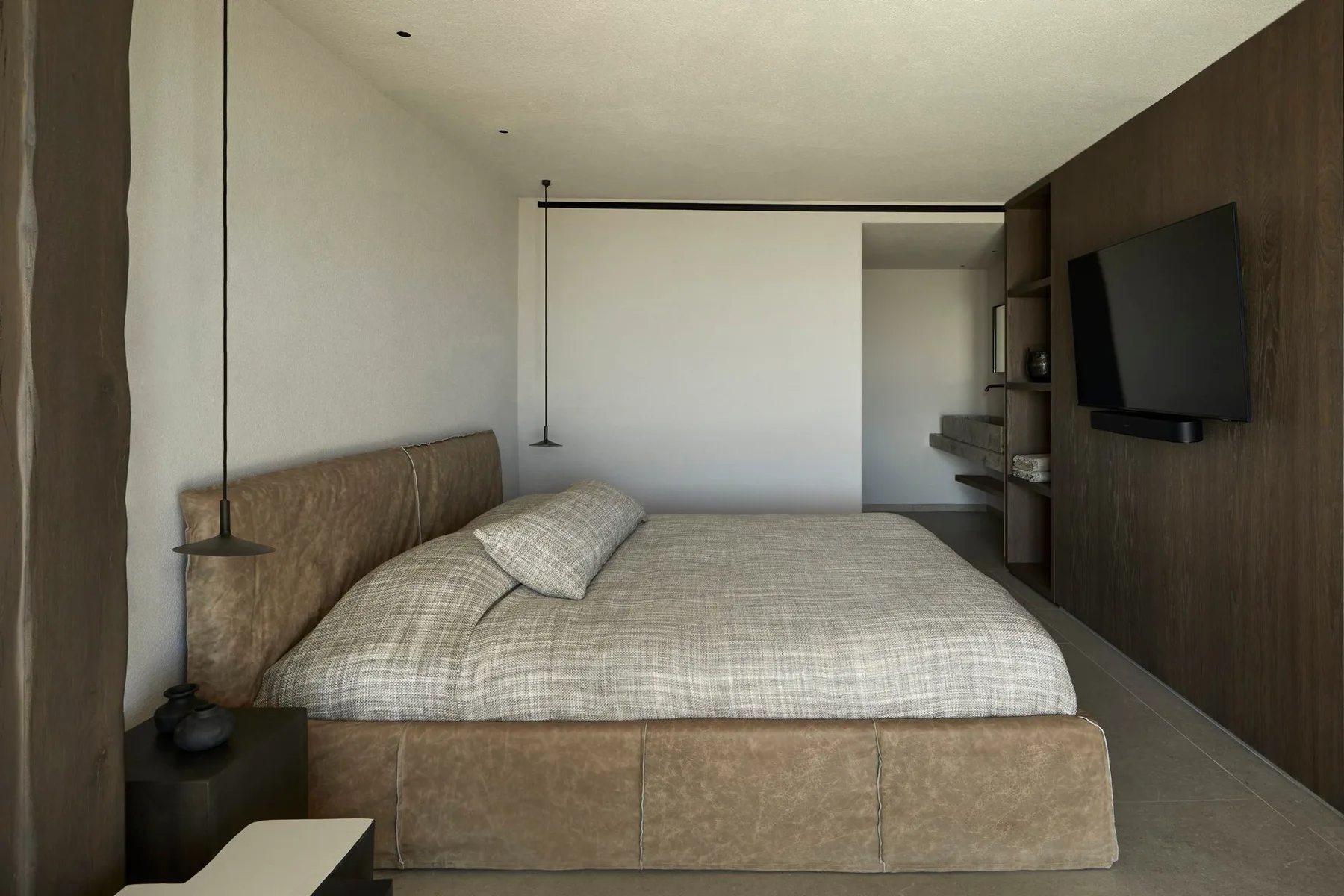 A bedroom with a large bed and a television mounted on the wall.