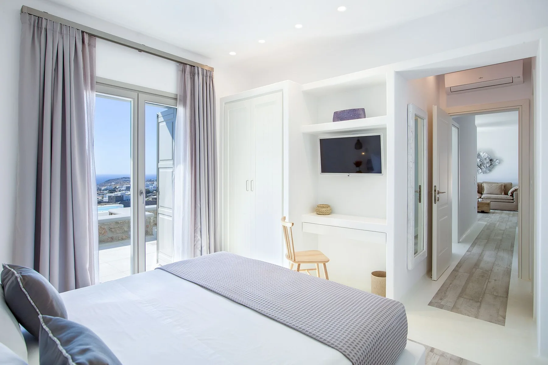A bright bedroom with a bed, a window, and an open doorway to the hall.