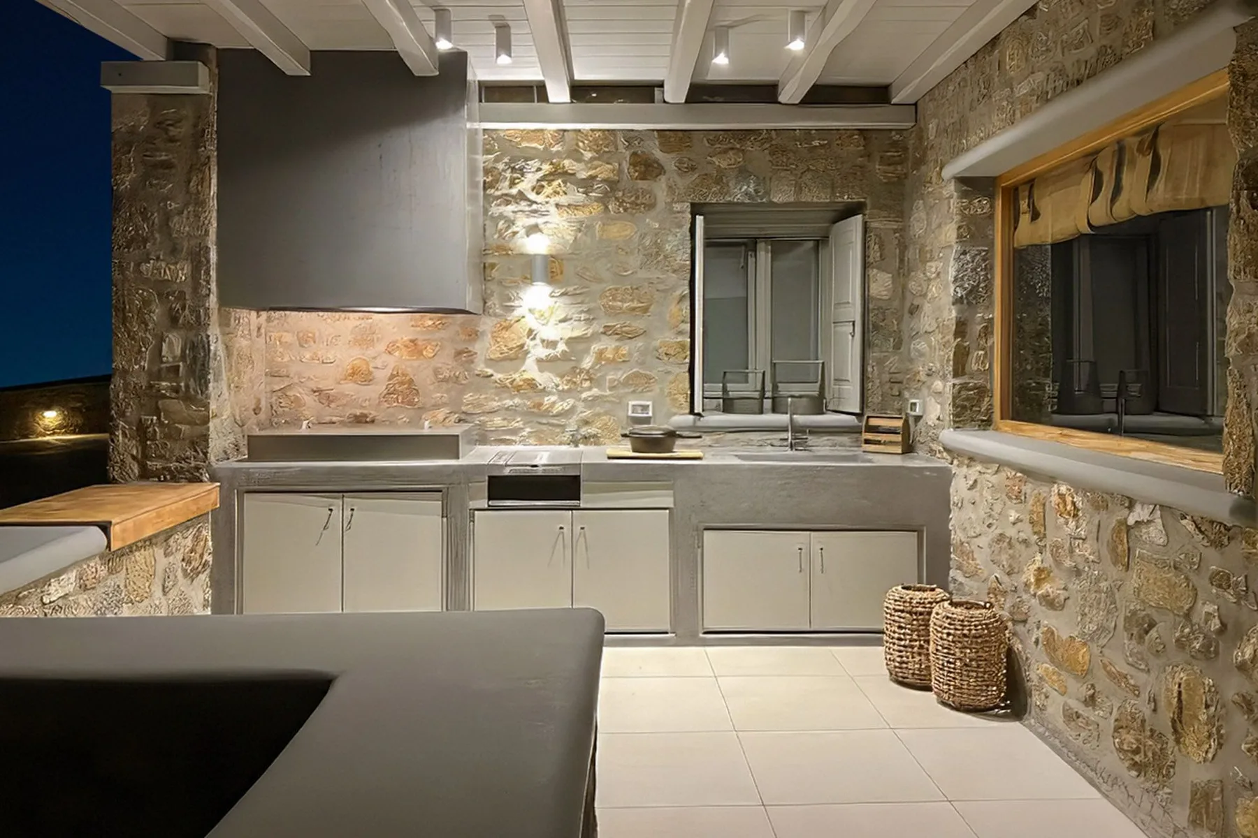 A stone-clad kitchen with pale cabinets, a tiled floor, and a large window.