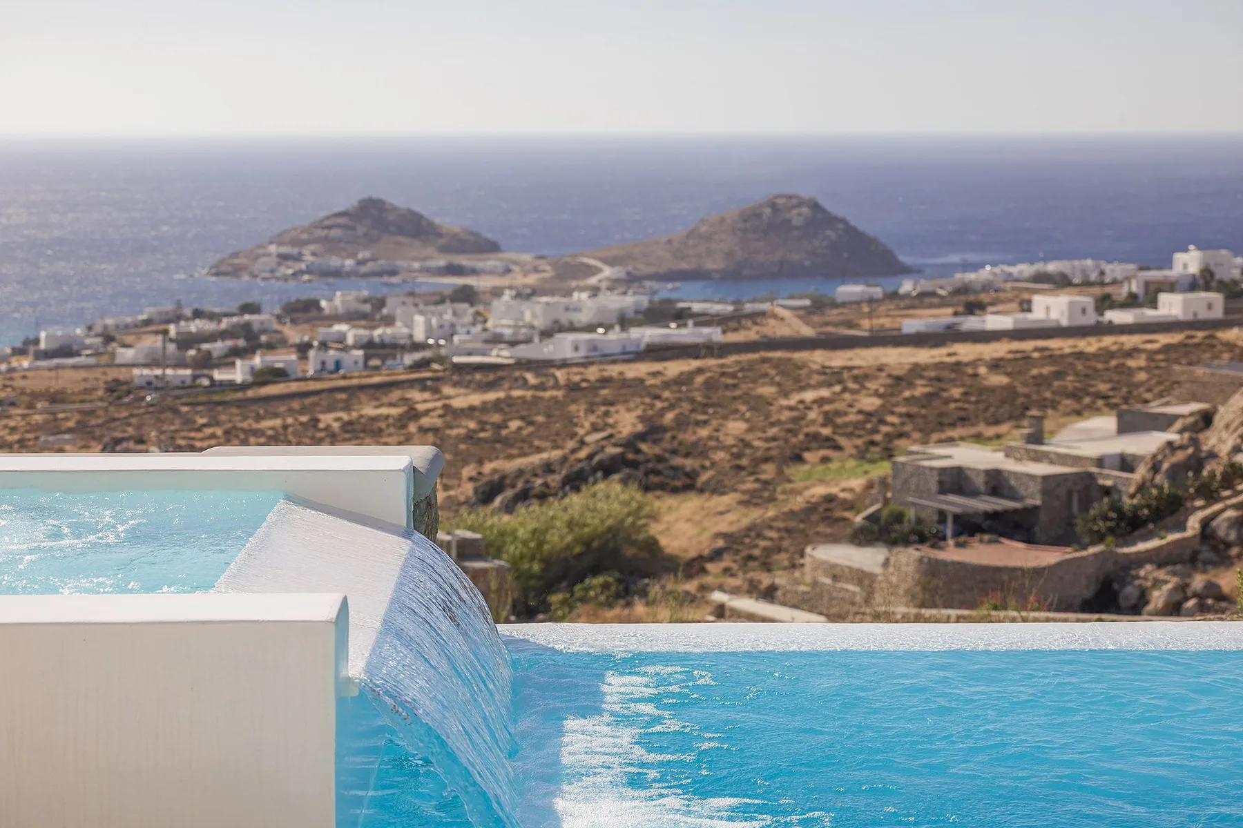 An infinity pool overlooks a coastal landscape and two rocky islands.