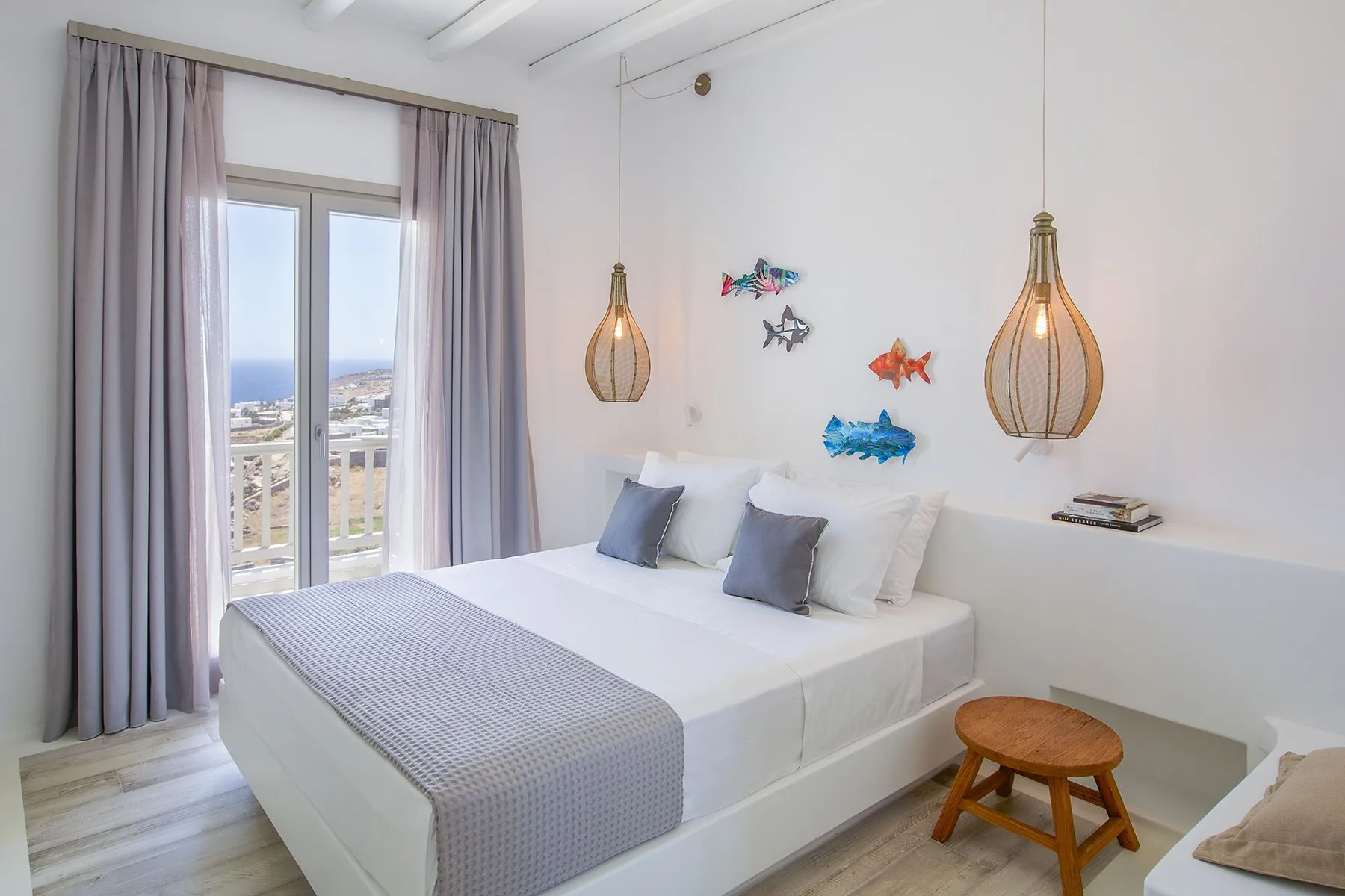 A bright bedroom with a neatly made bed and colorful fish decorations on the wall.