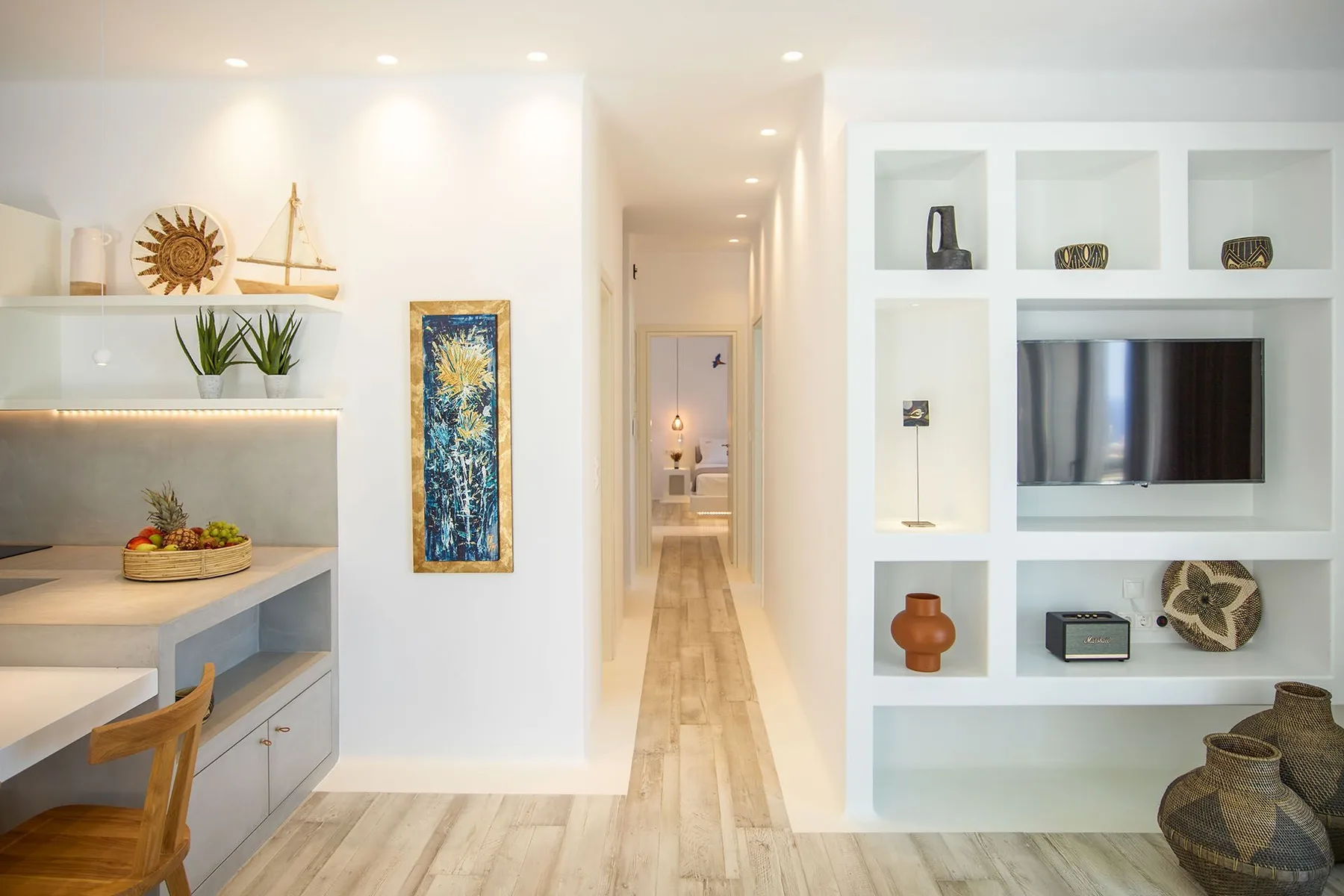 A bright living area with built-in shelving and a television beside a hallway.