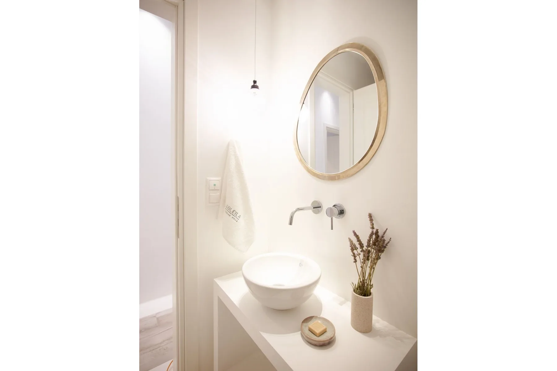 A bright bathroom vanity with a vessel sink and round mirror.