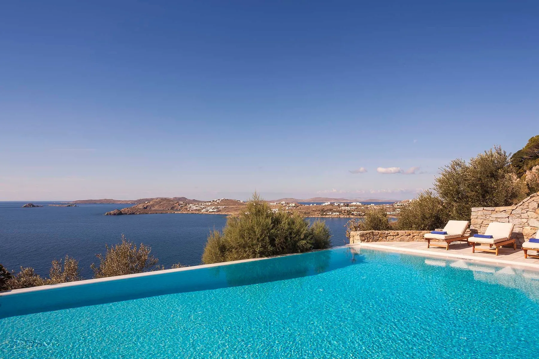 Una piscina con vistas al mar y tumbonas junto al borde.