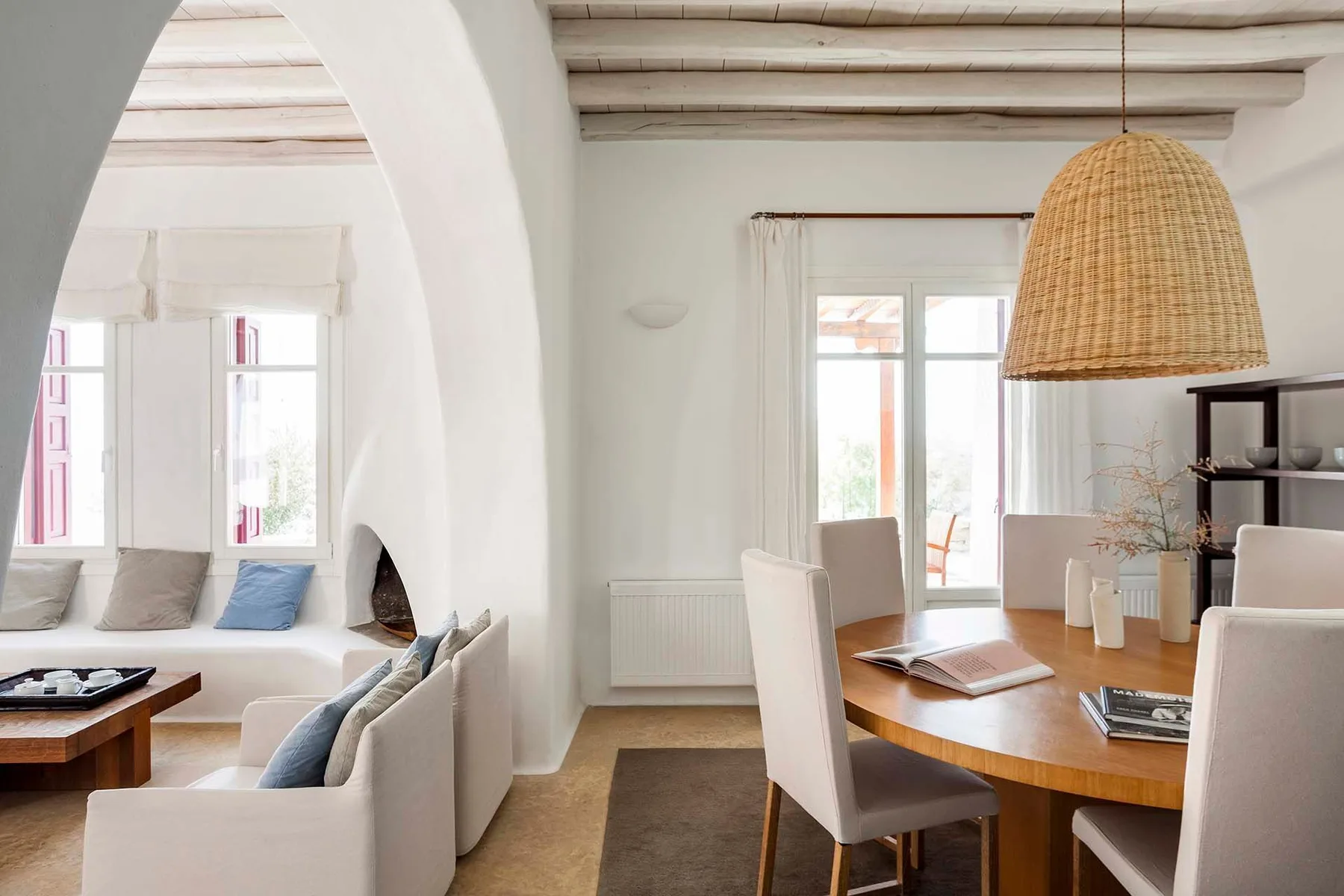 Una luminosa sala de estar y comedor con asientos blancos y una mesa de madera.