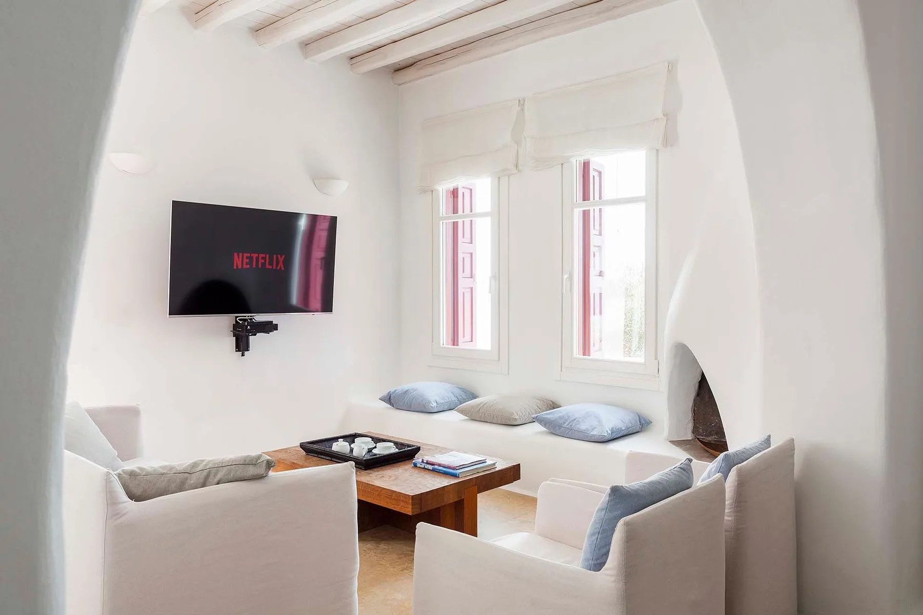 Una sala luminosa con asientos, una mesa de centro y un televisor en la pared.
