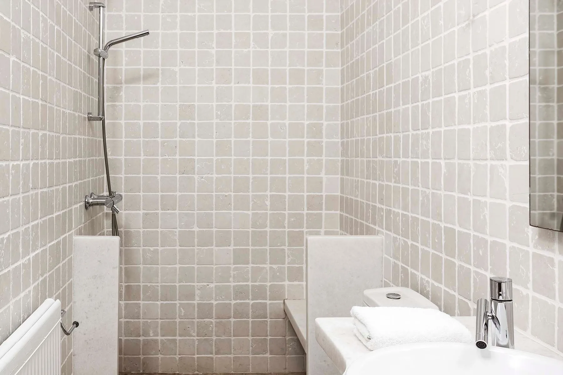 Un baño con azulejos, ducha y lavabo blanco.