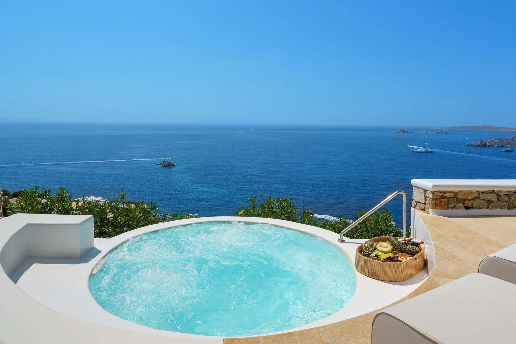A round pool sits on a terrace overlooking the sea.