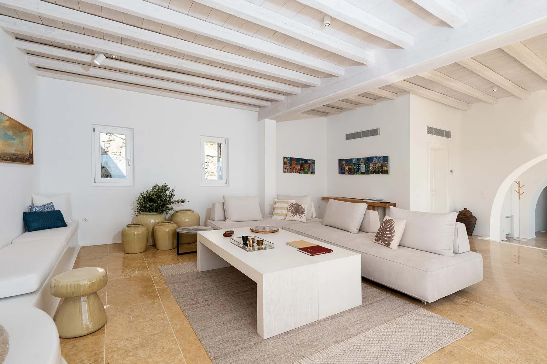 A bright living room with white seating arranged around a low coffee table.