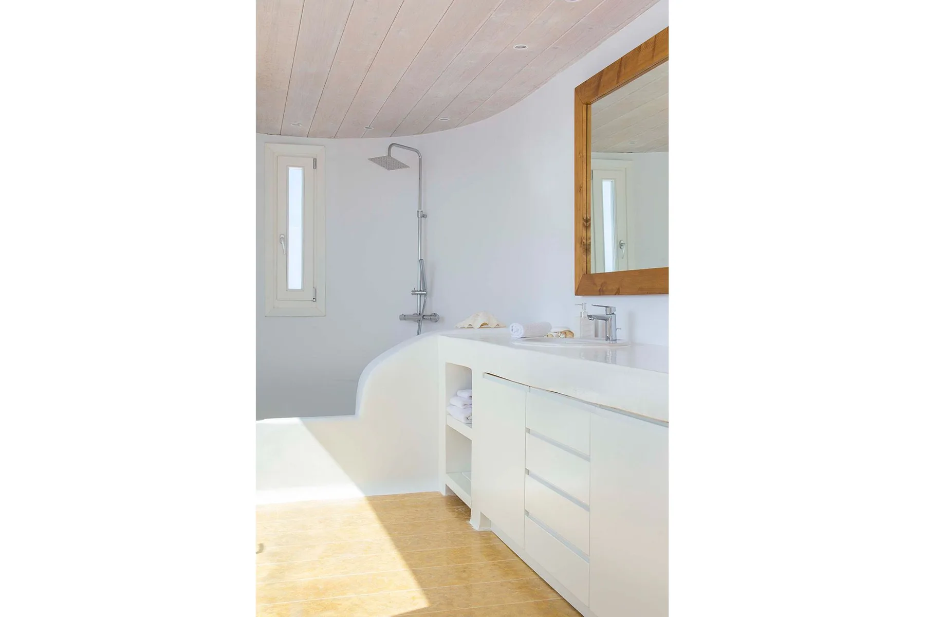 A bright bathroom with a shower, white vanity, and large mirror.