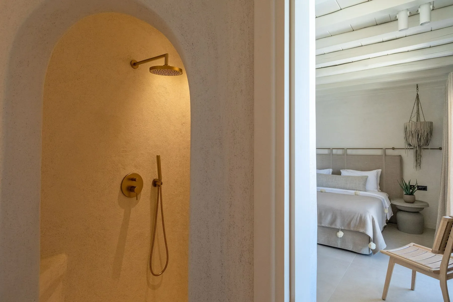 A bedroom with a bed and a view of an arched shower area.