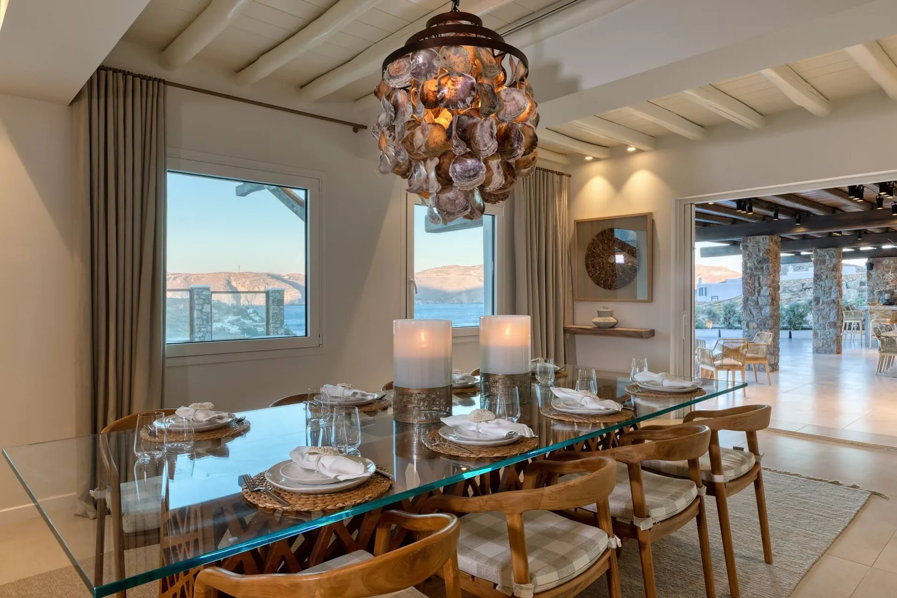 A dining area with a long glass table set beneath a decorative pendant light.