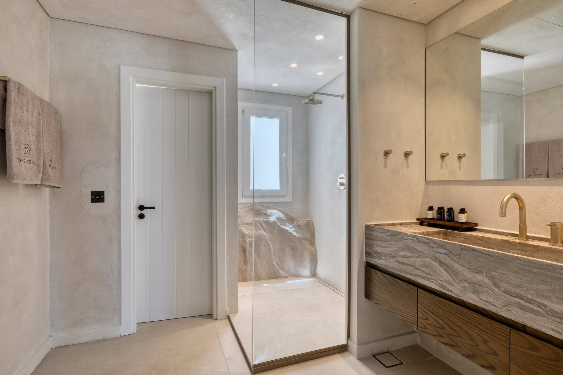 A bright bathroom with a glass shower, vanity, and large mirror.