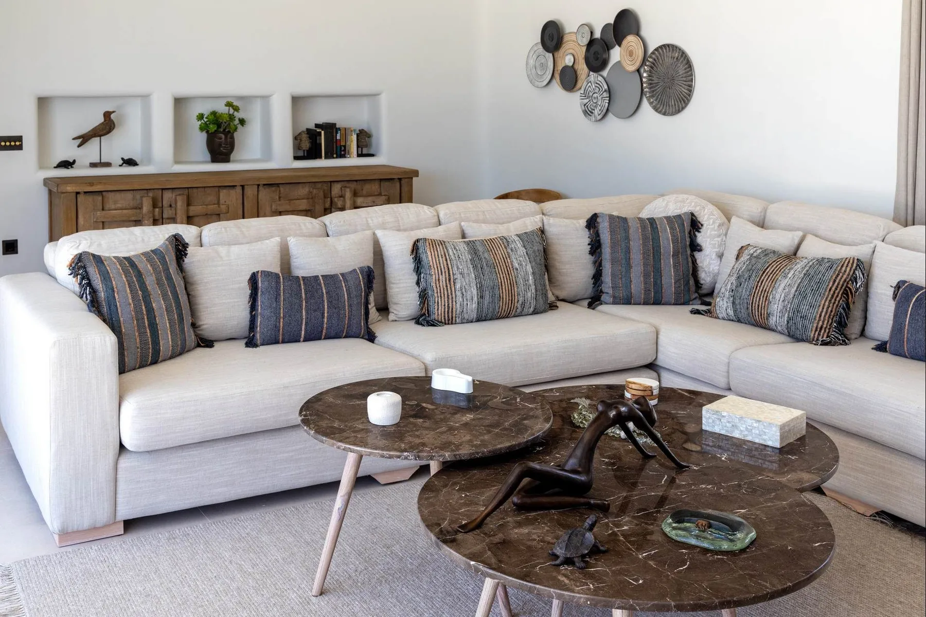 A bright living room with a large sectional seating area and round coffee tables.