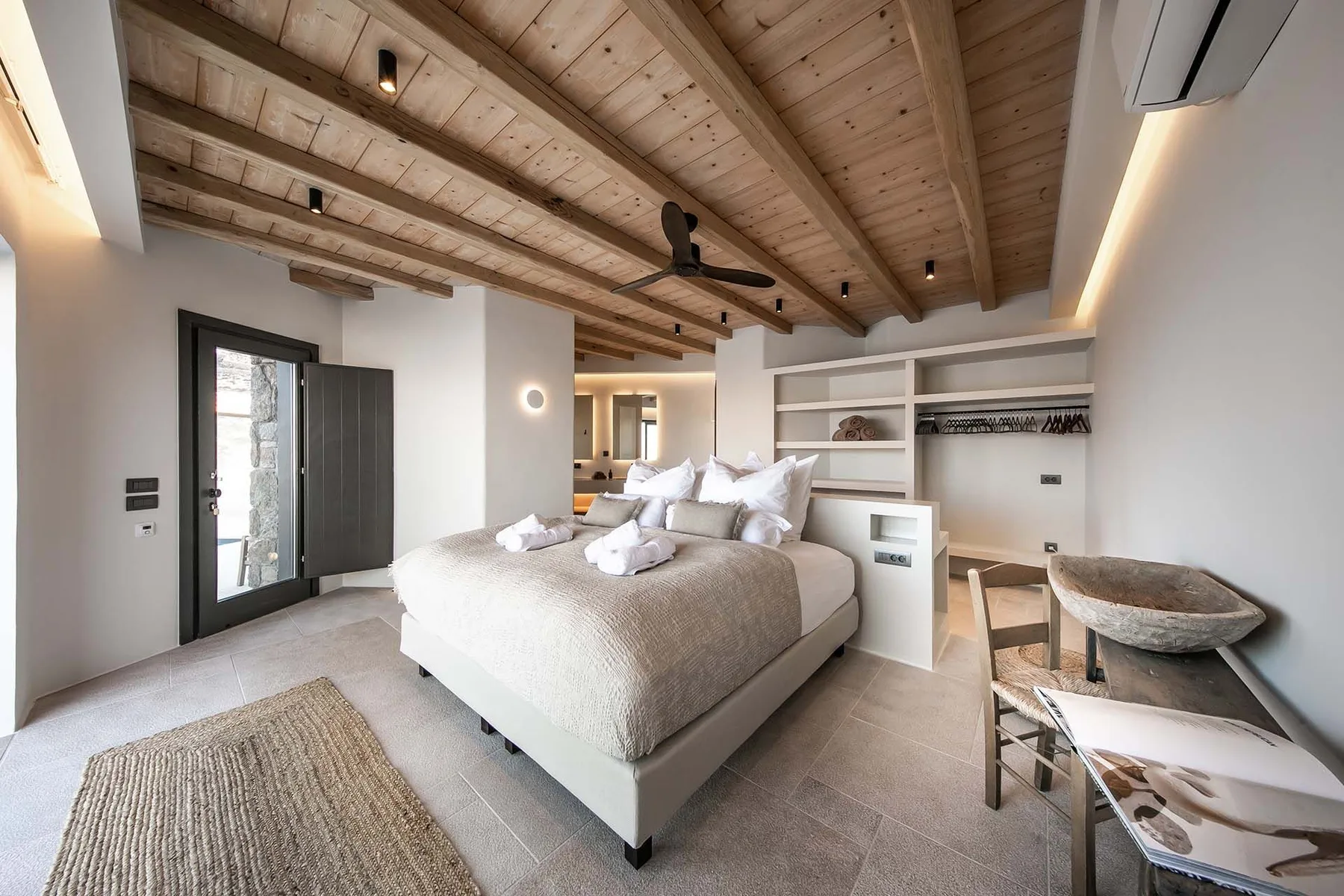 A bedroom with a large bed beneath a sloped wooden ceiling.