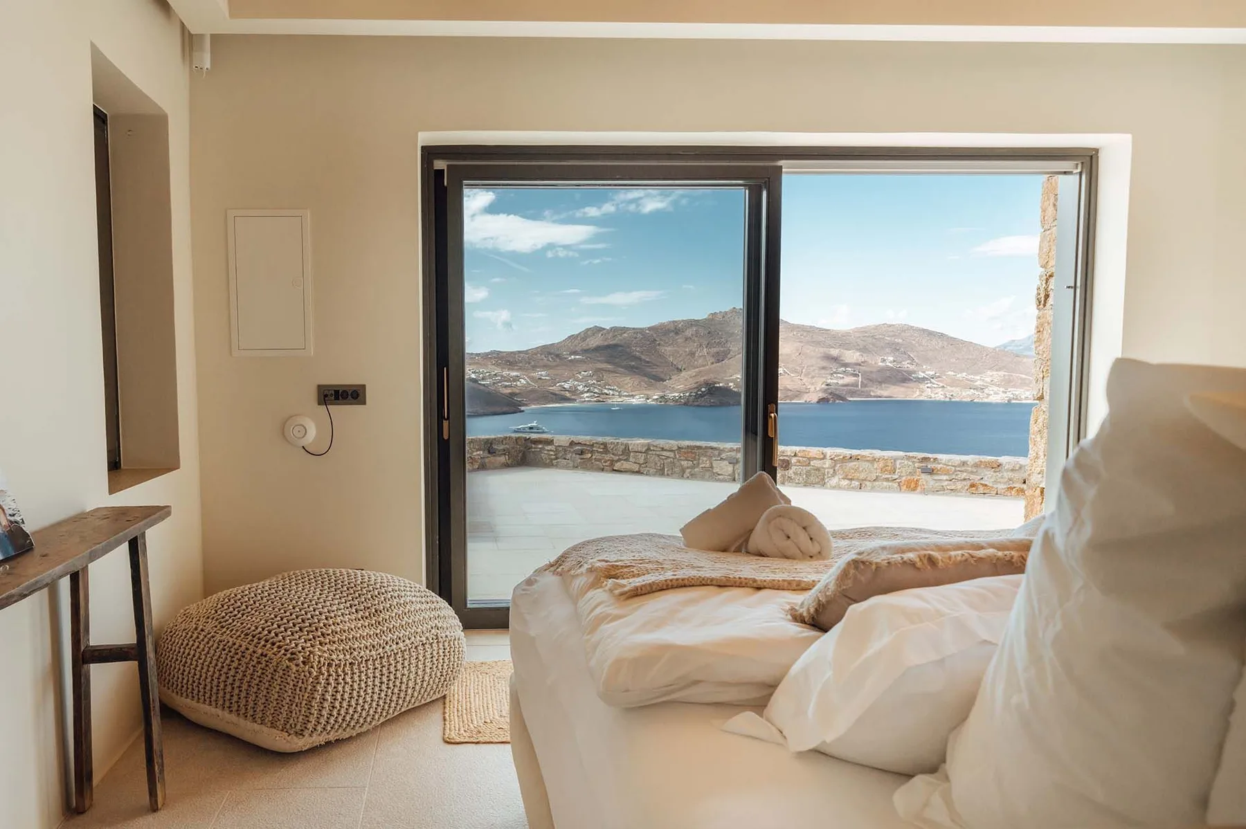 A bedroom with a large window overlooking a lake and mountains.