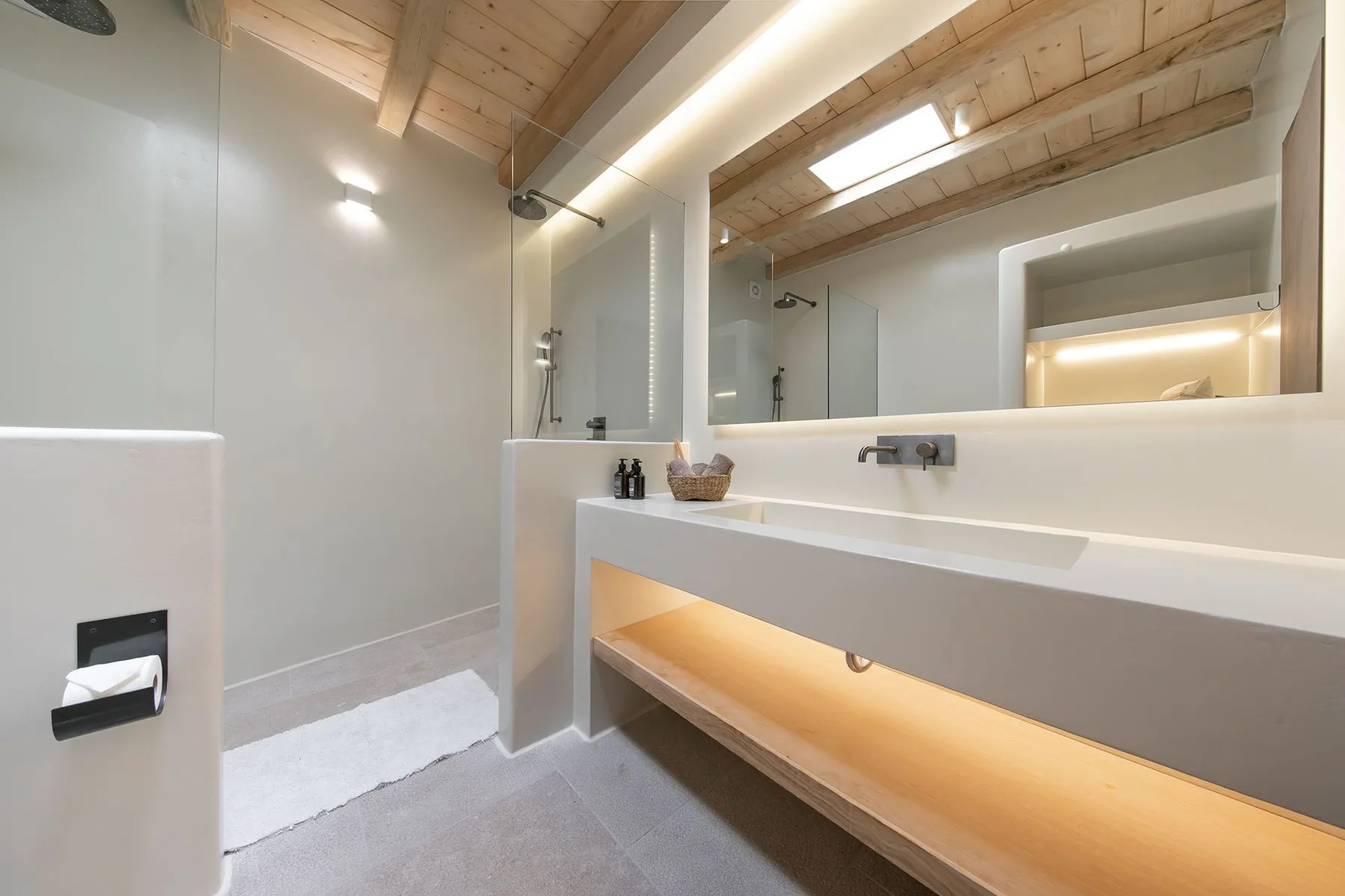 A bright bathroom with a large mirror above a long sink counter.