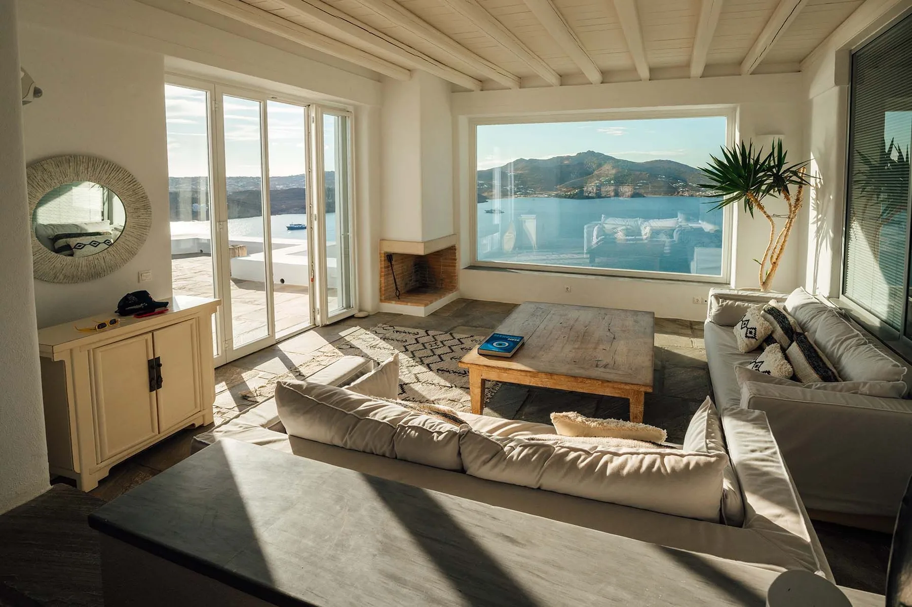 A bright living room opens onto a large window overlooking the water.