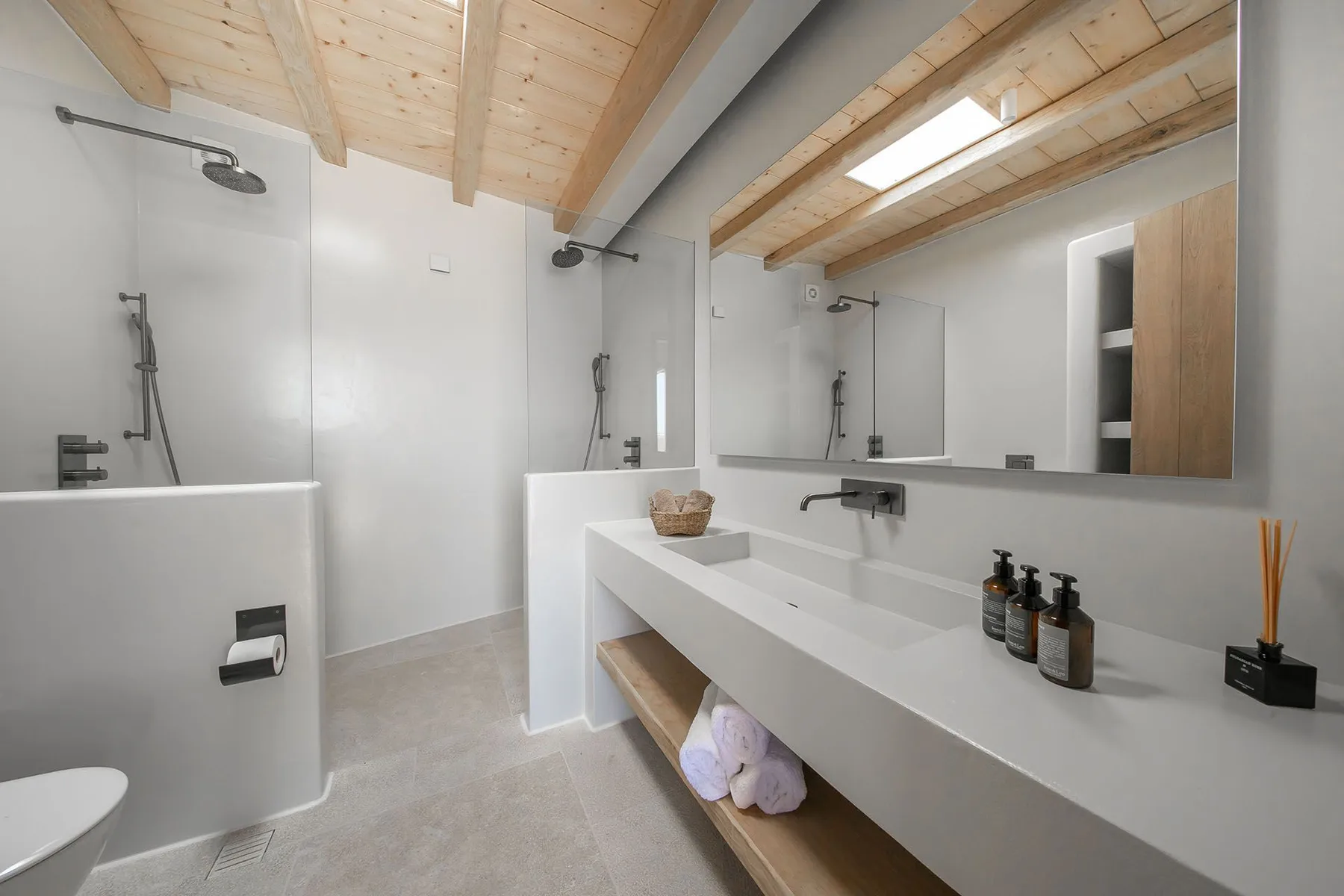 A modern bathroom with a long vanity, wall mirror, and walk-in shower.