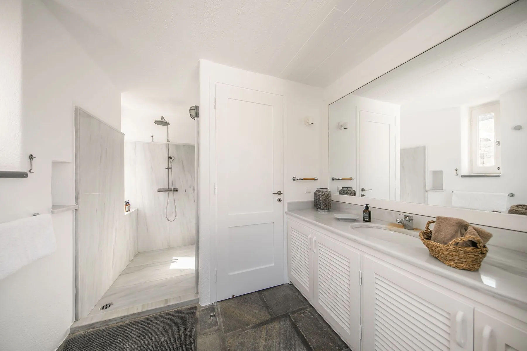 A bright bathroom with a long vanity and an open shower area.