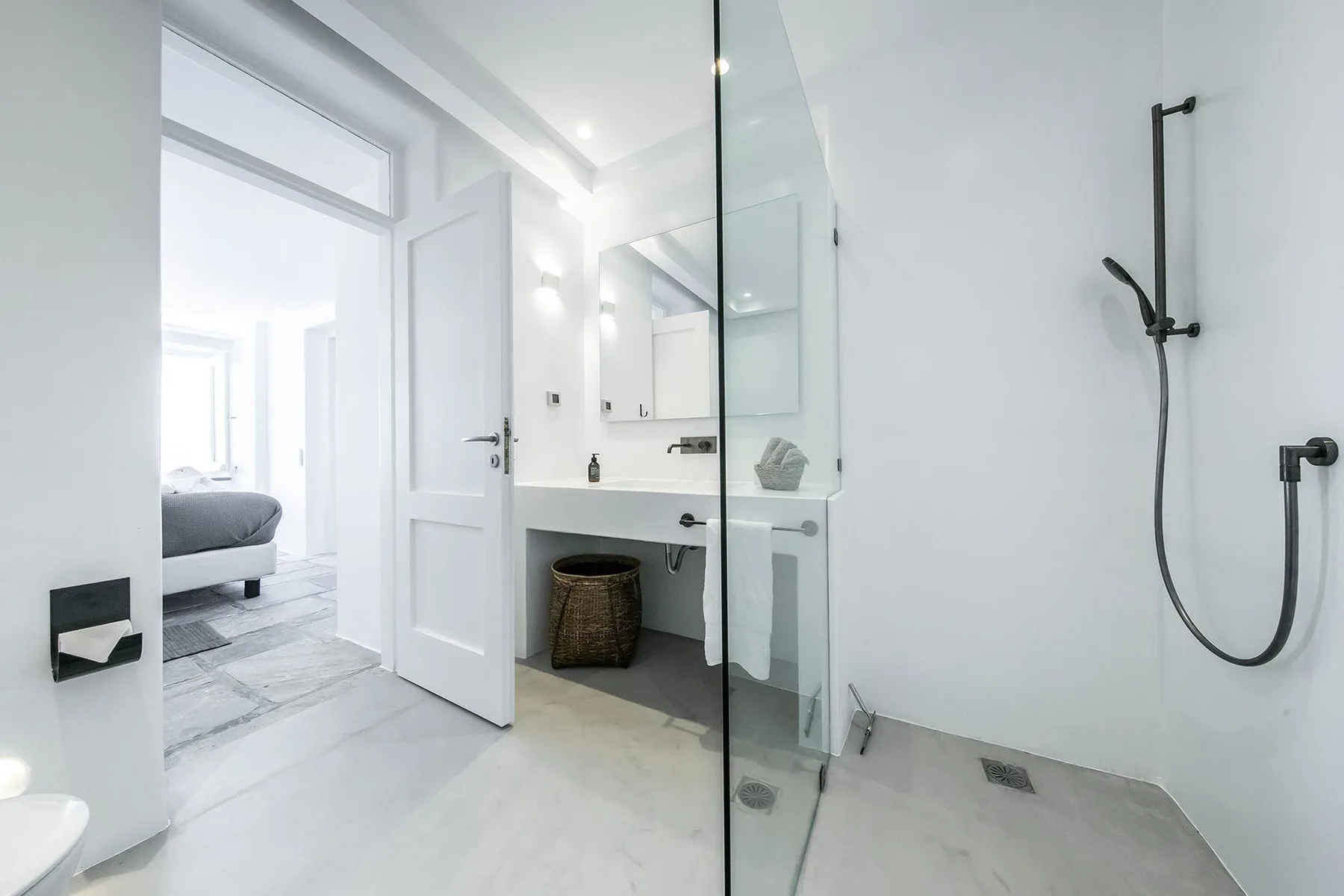 A bright bathroom with a walk-in shower and a sink beside an open door.