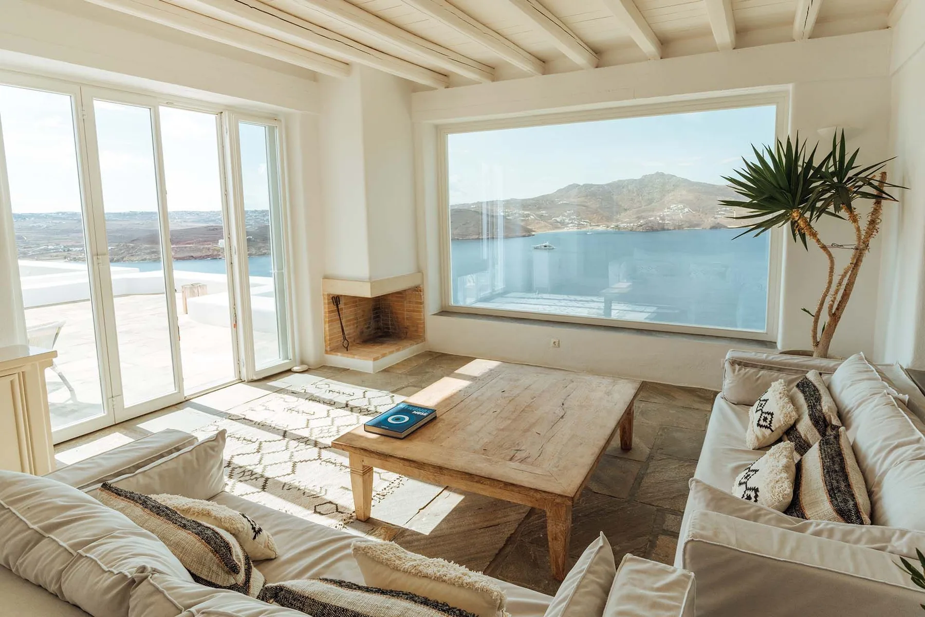 A bright living room with seating and a large window overlooking the water.