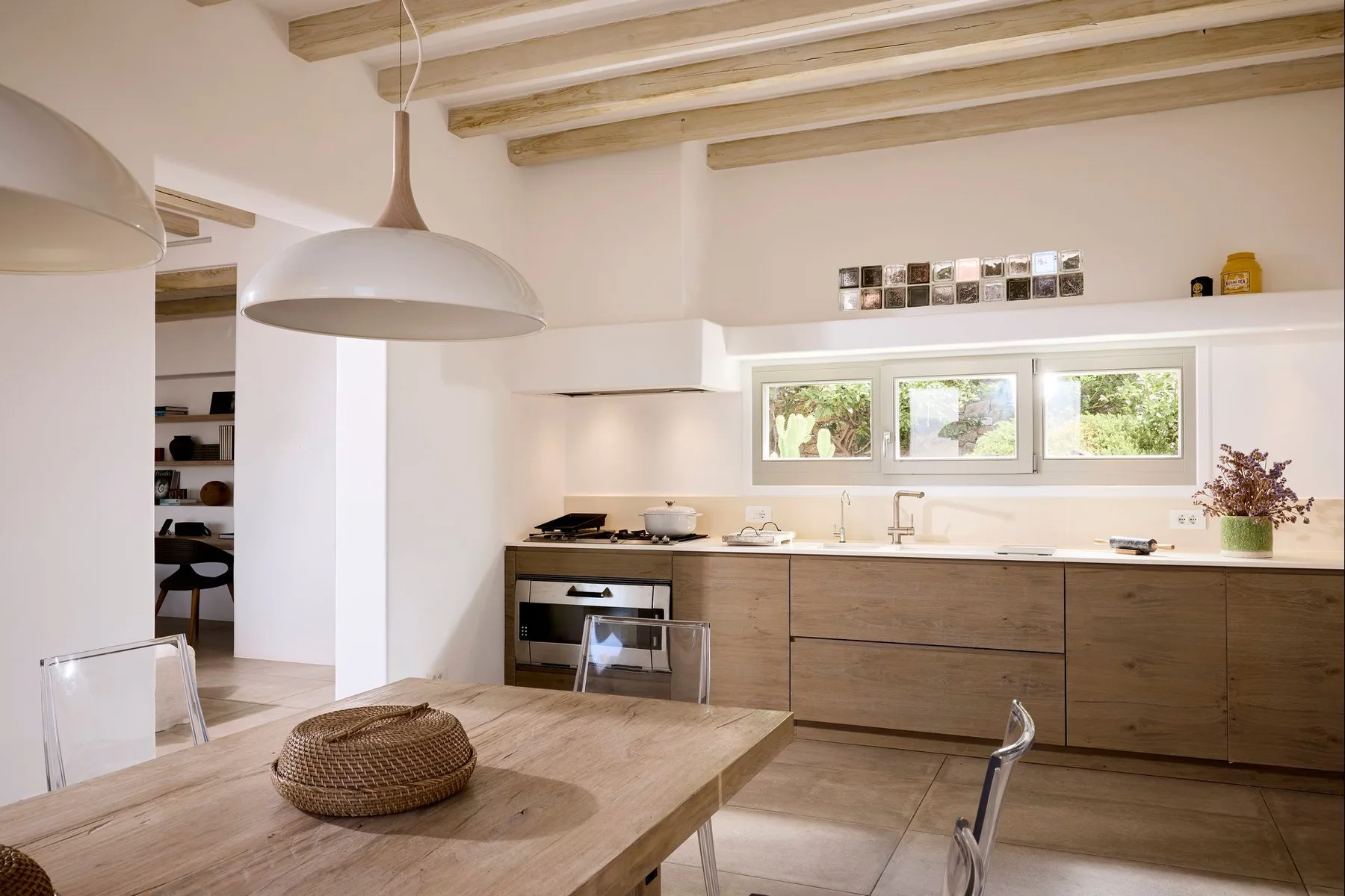 Una cocina luminosa con gabinetes de madera, vigas expuestas y una mesa de comedor.