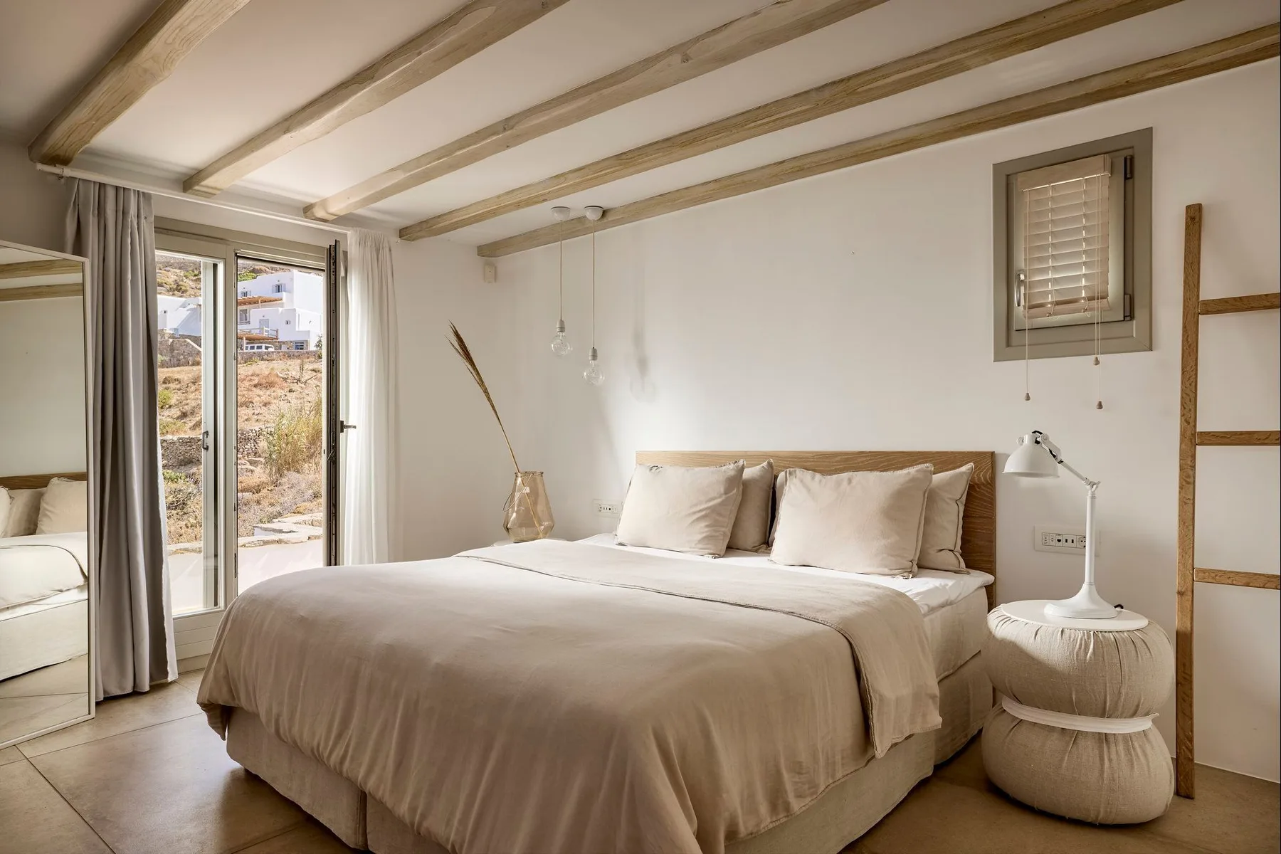 Un dormitorio con una cama bien tendida junto a puertas de vidrio con vistas al exterior.