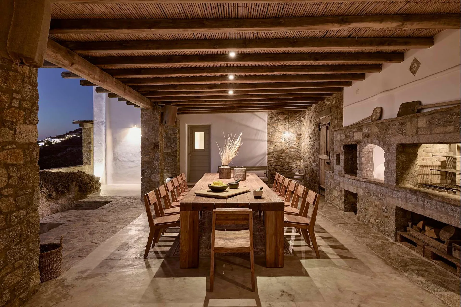 Comedor con una larga mesa de madera bajo vigas expuestas en el techo.