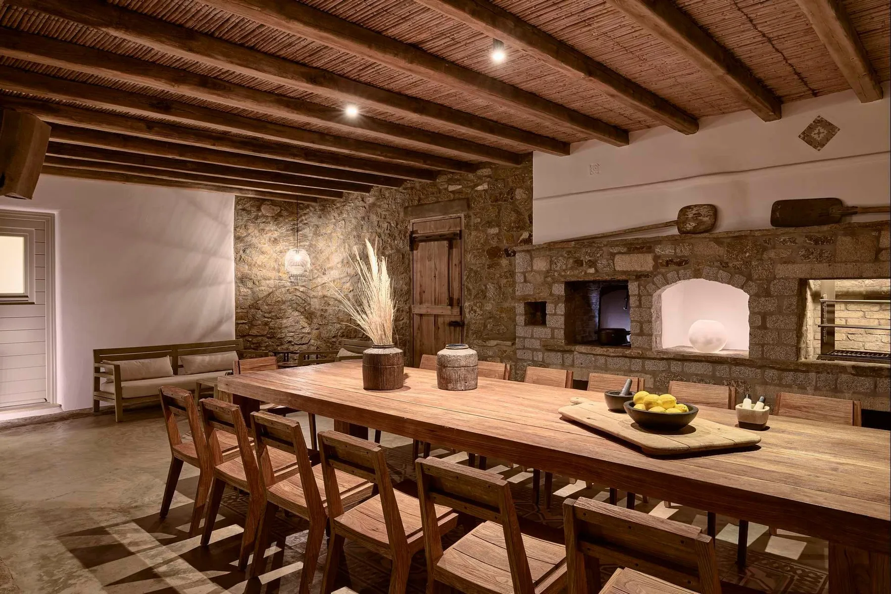 Un comedor rústico con una larga mesa de madera bajo vigas expuestas.