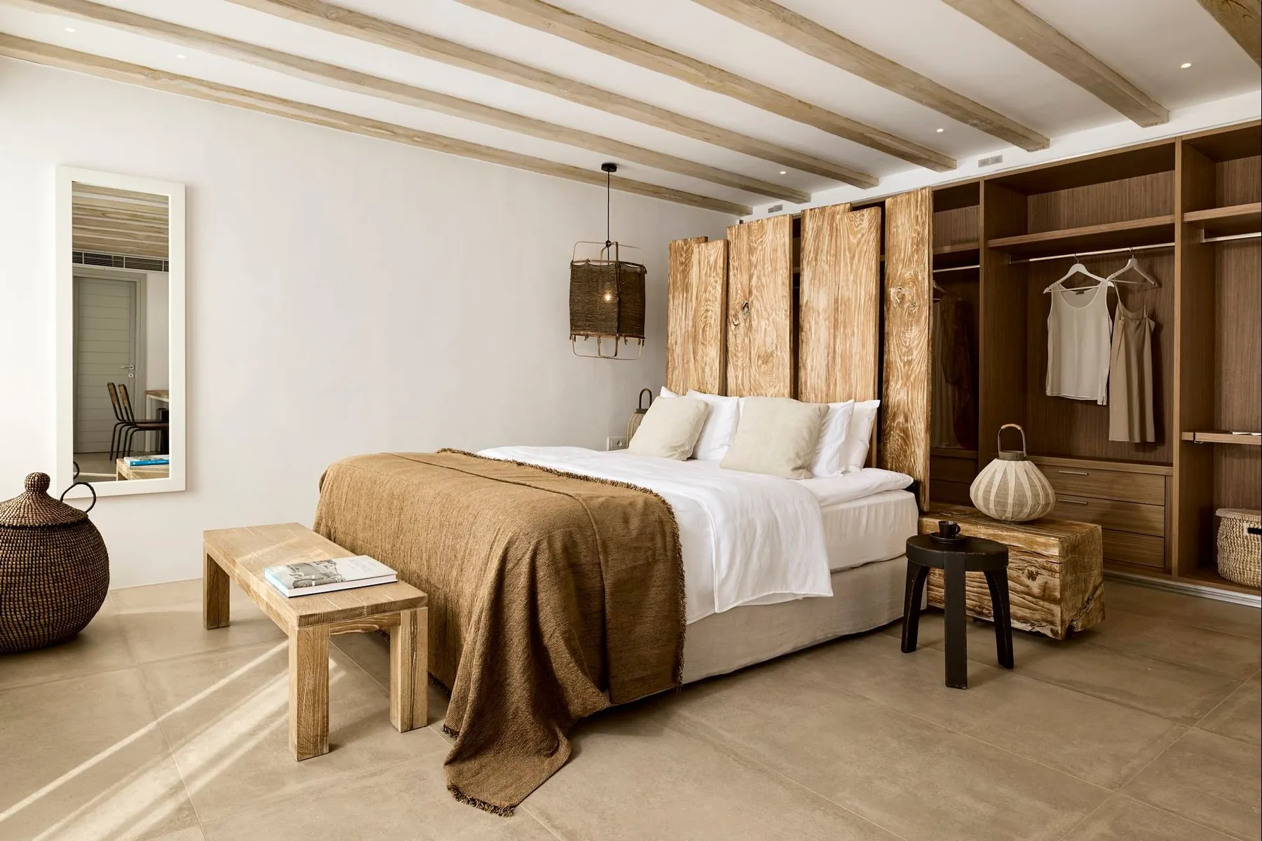 Dormitorio con una cama, una mesa auxiliar y un armario de madera abierto.