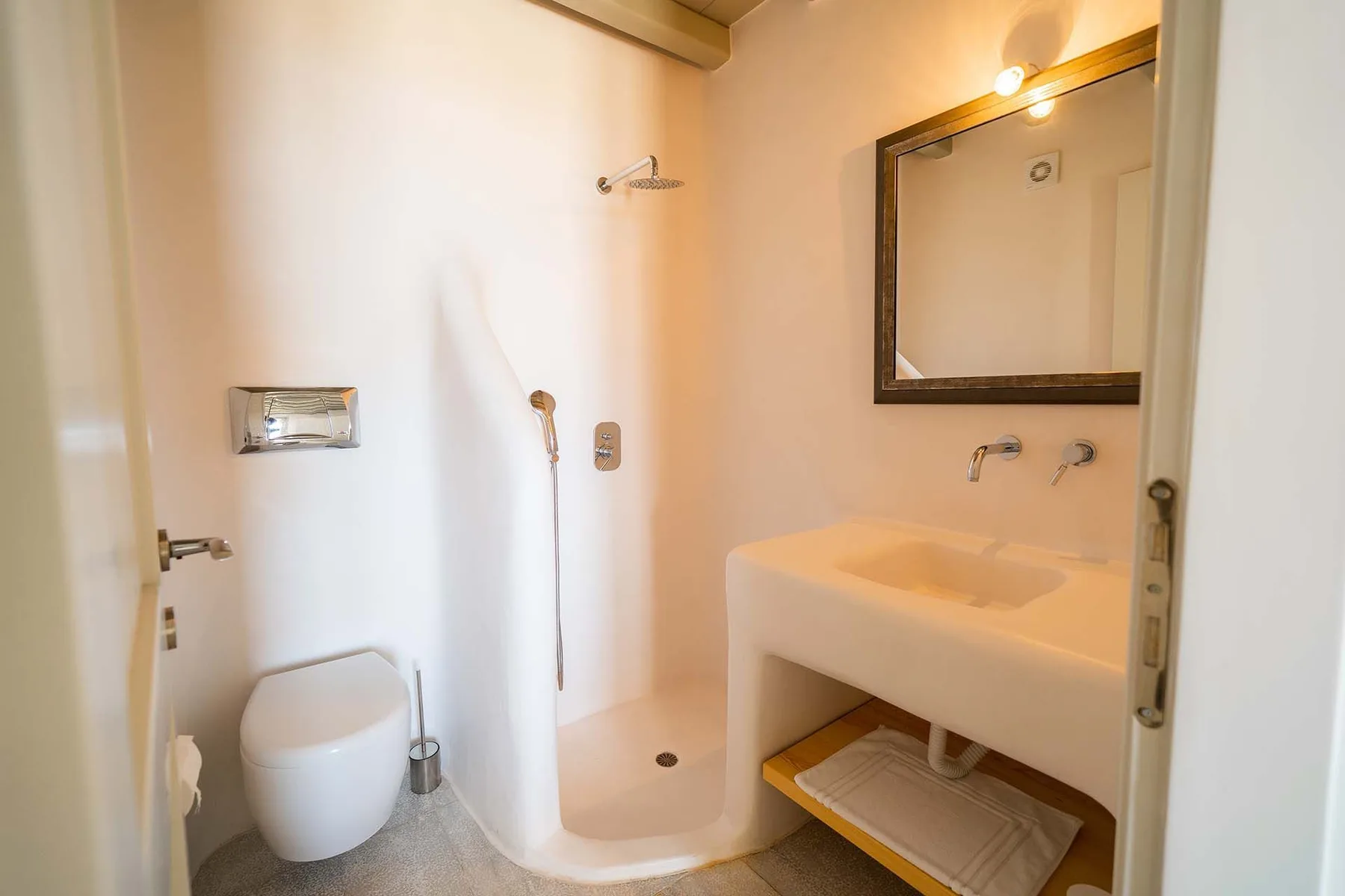 A bathroom with a shower and a sink beneath a wall mirror.